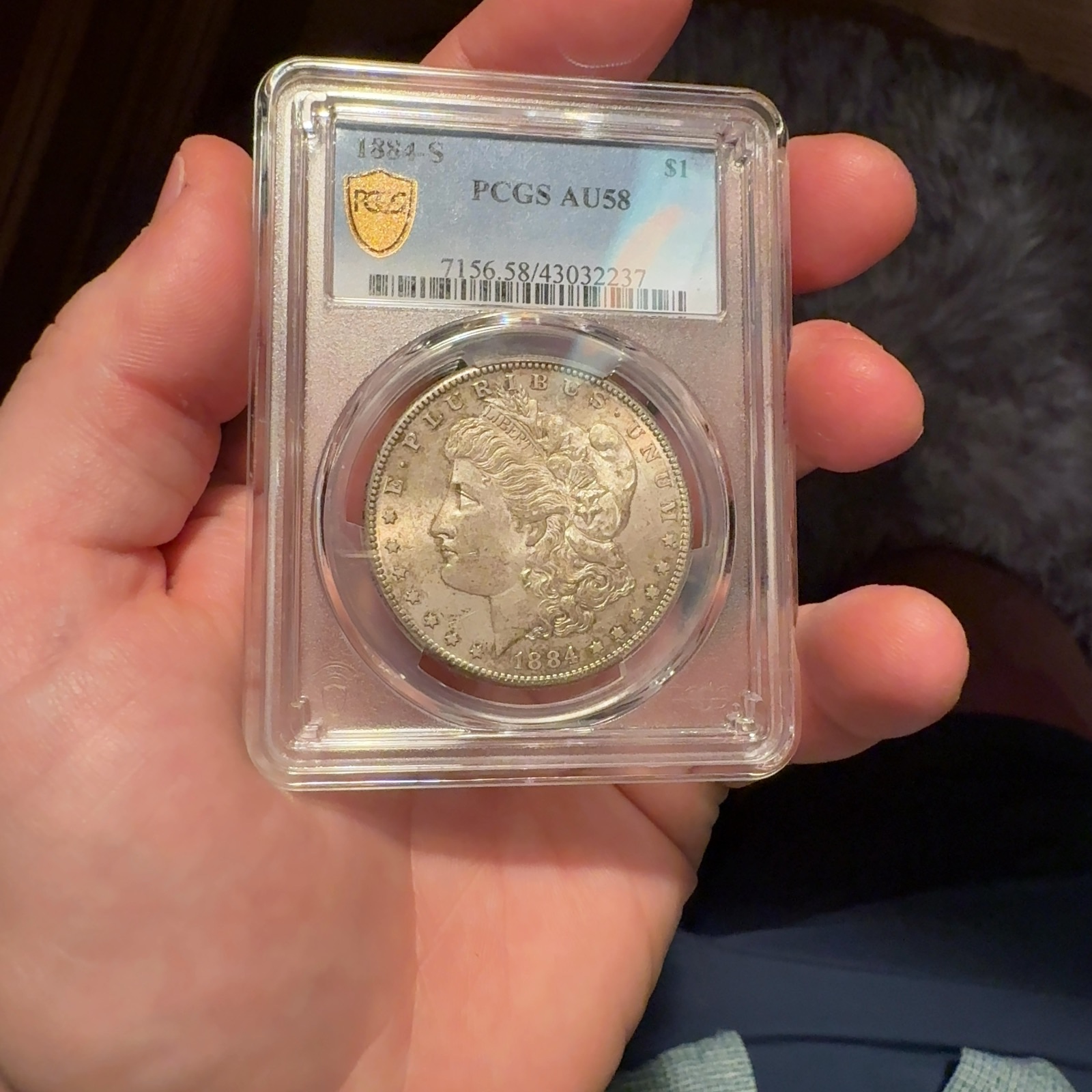 Handheld phone photograph 2 of the 1884-S Morgan Dollar in its holder