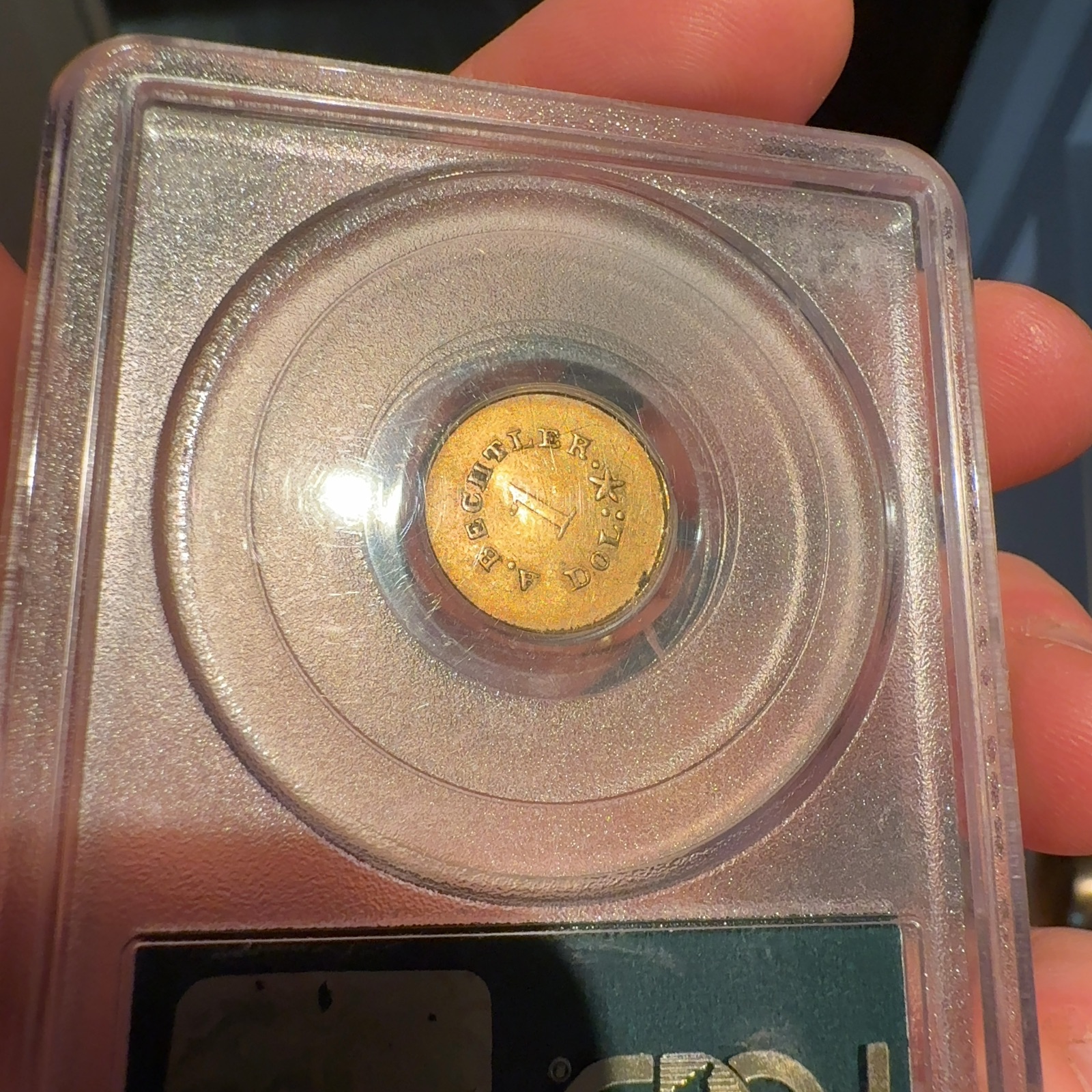 Handheld phone photograph 7 of the 1830s Bechtler Gold Dollar in its holder