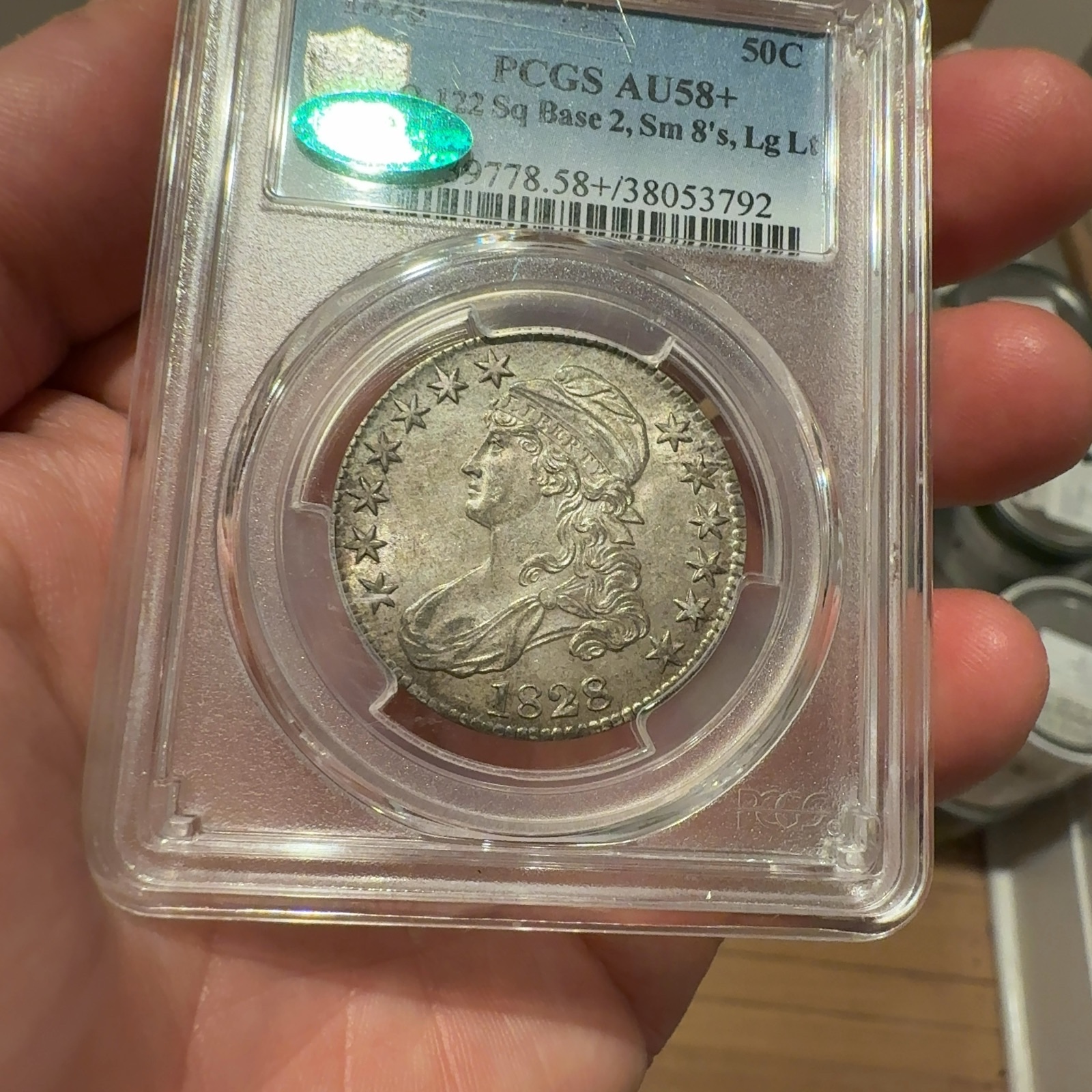 Handheld phone photograph 3 of the 1828 Capped Bust Half Dollar in its holder