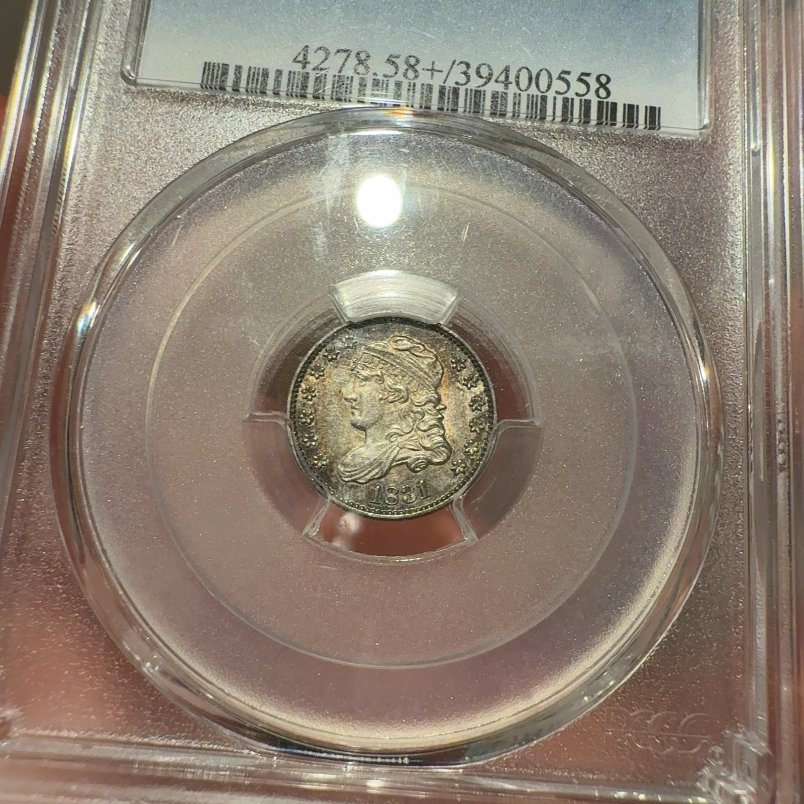 Handheld phone photograph 2 of the 1831 Capped Bust Half Dime in its holder