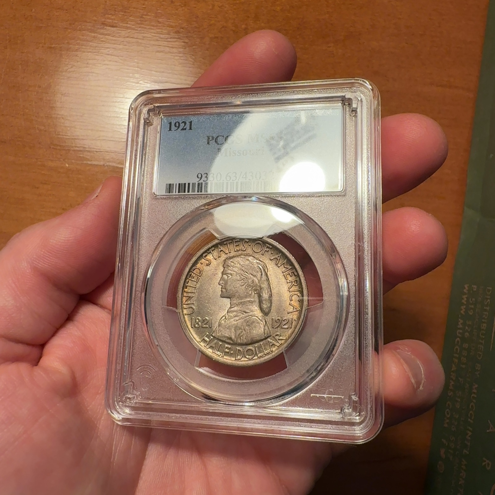 Handheld phone photograph 2 of the 1921 Missouri Half Dollar in its holder