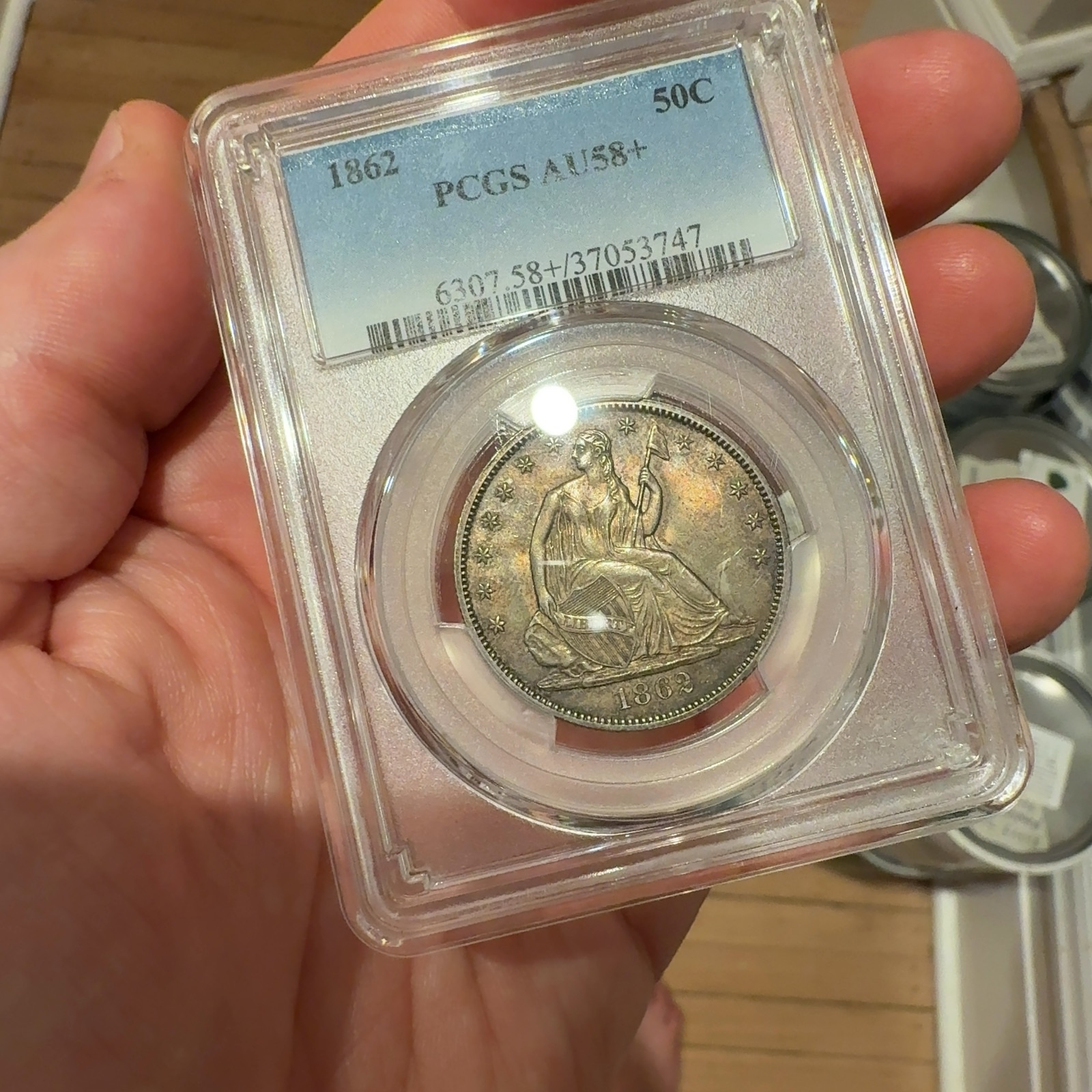 Handheld phone photograph 4 of the 1862 Seated Liberty Half Dollar in its holder