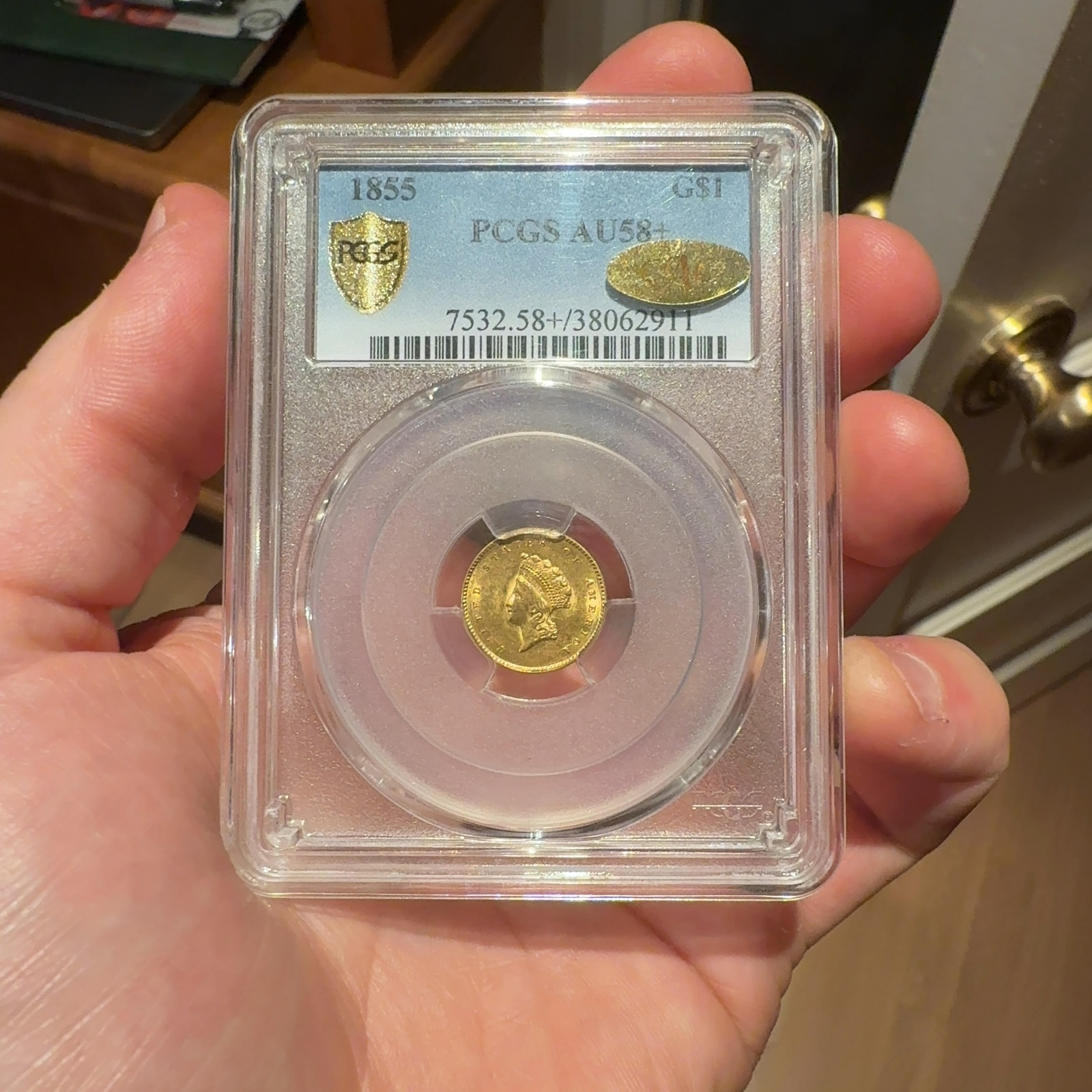 Handheld phone photograph 1 of the 1855 Gold Dollar in its holder