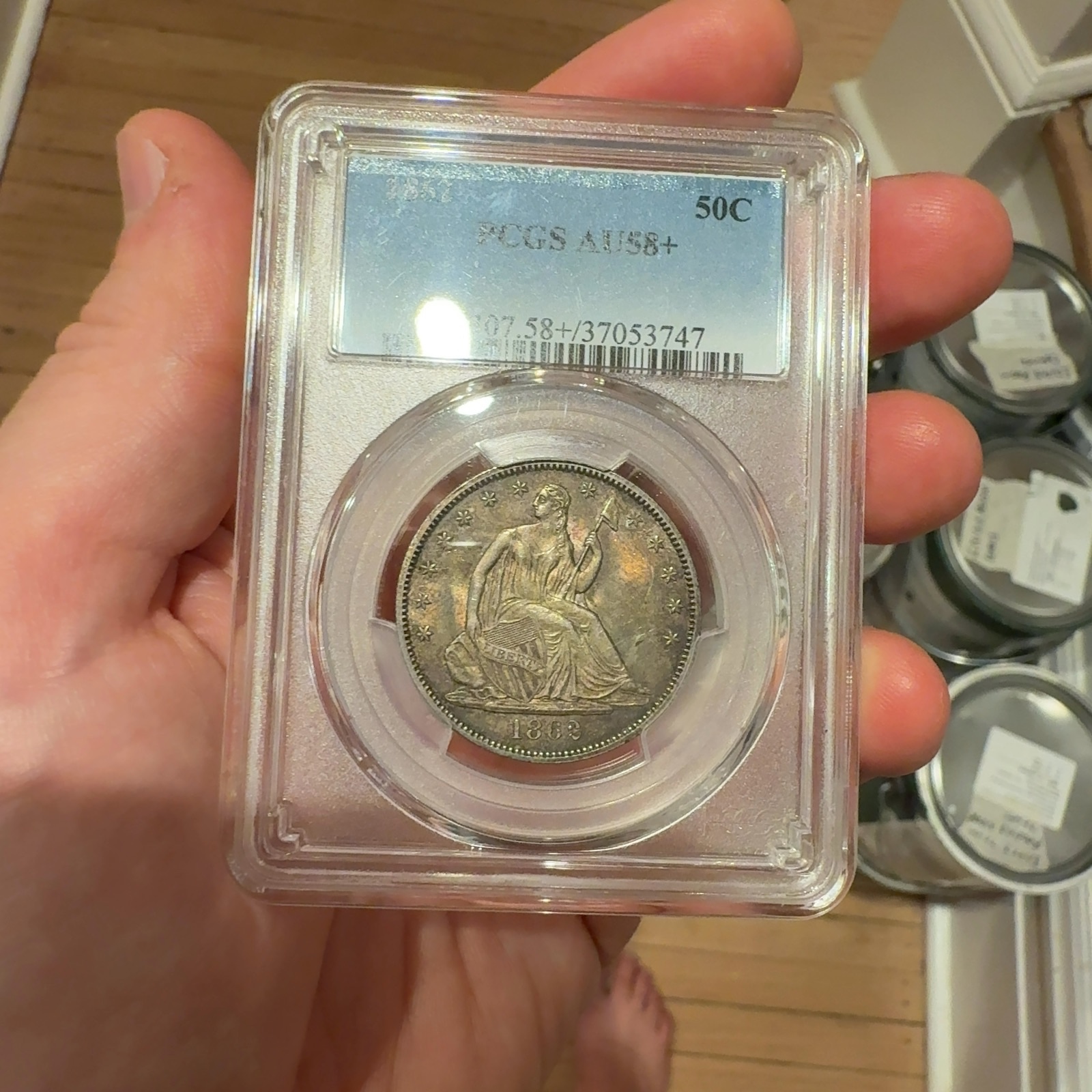 Handheld phone photograph 3 of the 1862 Seated Liberty Half Dollar in its holder