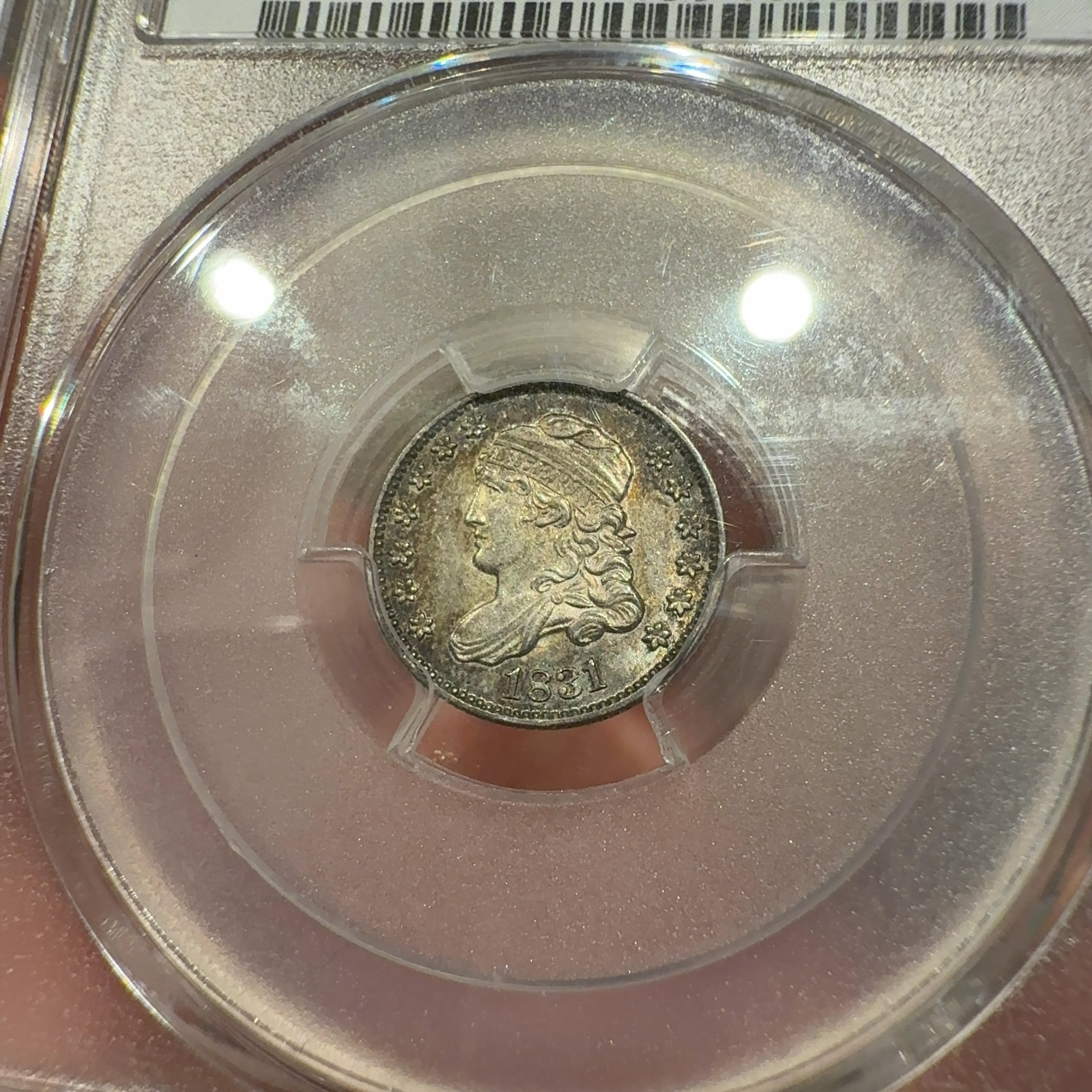 Handheld phone photograph 4 of the 1831 Capped Bust Half Dime in its holder
