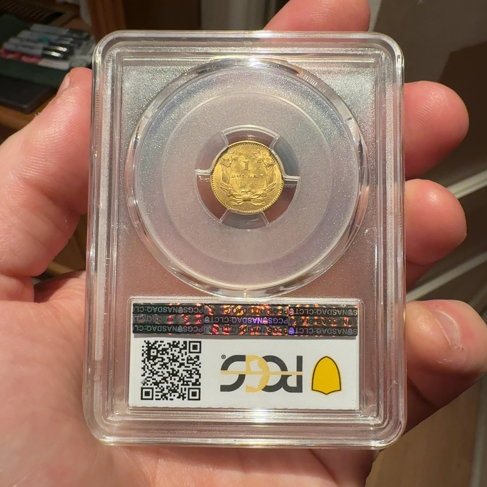 Handheld phone photograph 5 of the 1855 Gold Dollar in its holder