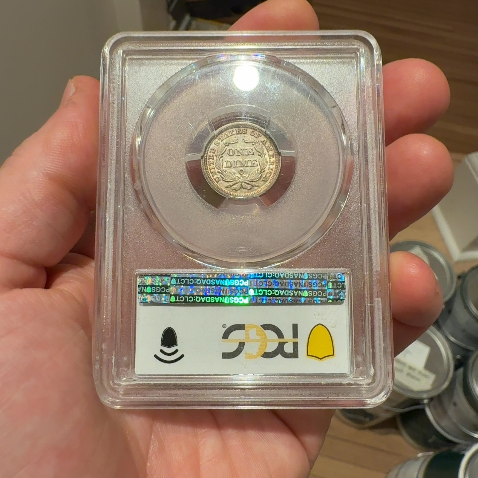 Handheld phone photograph 5 of the 1853-O Seated Liberty Dime in its holder