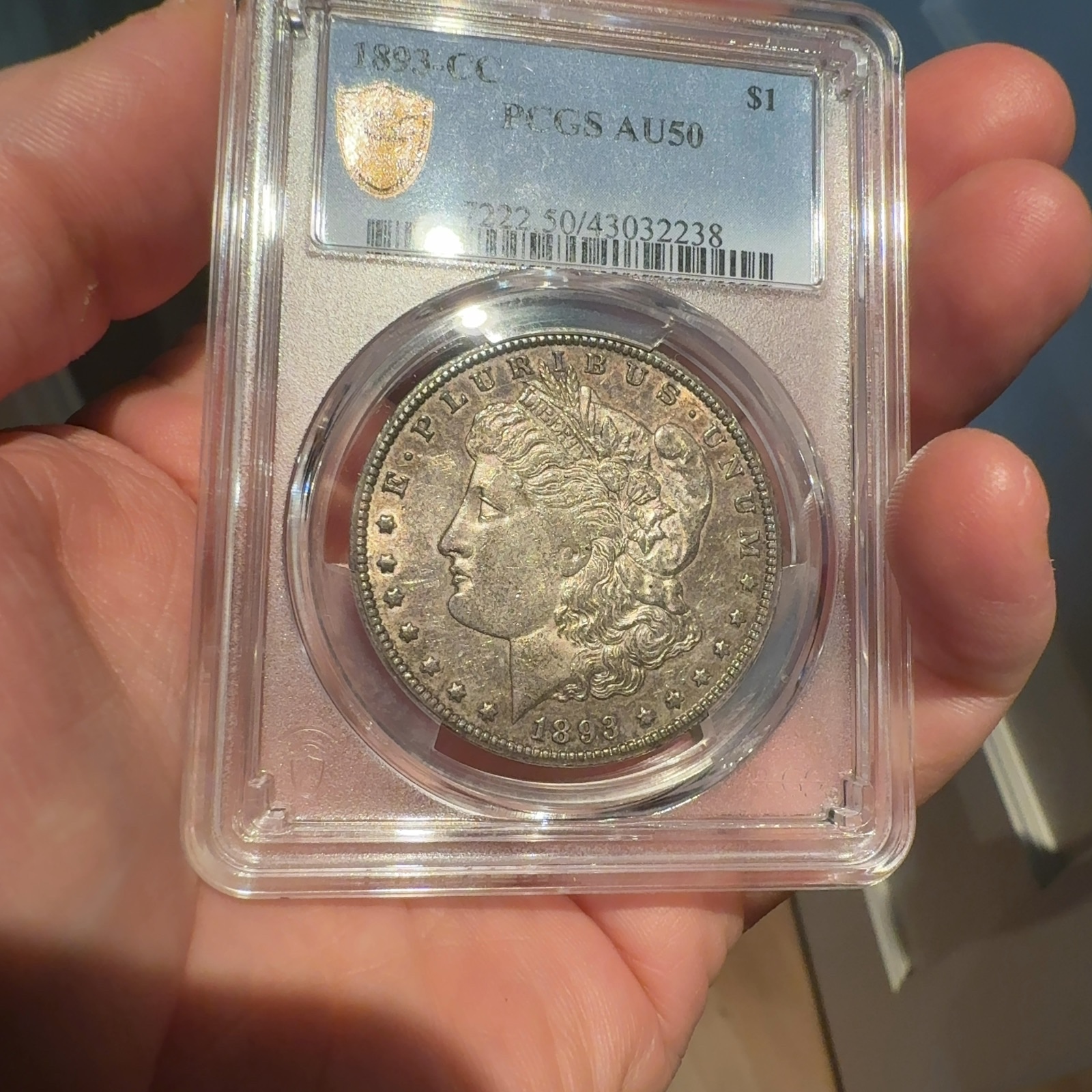 Handheld phone photograph 1 of the 1893-CC Morgan Dollar in its holder