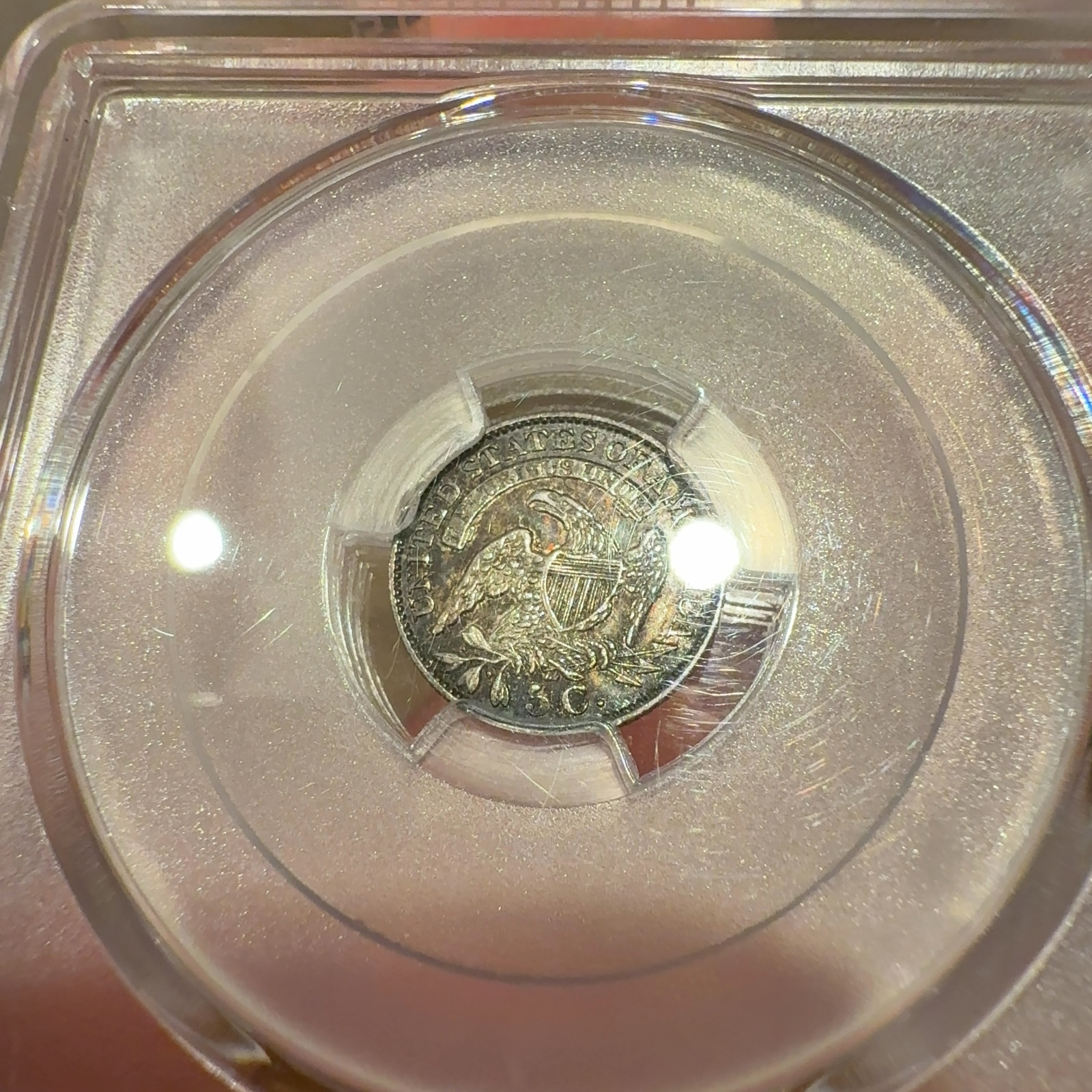 Handheld phone photograph 8 of the 1831 Capped Bust Half Dime in its holder