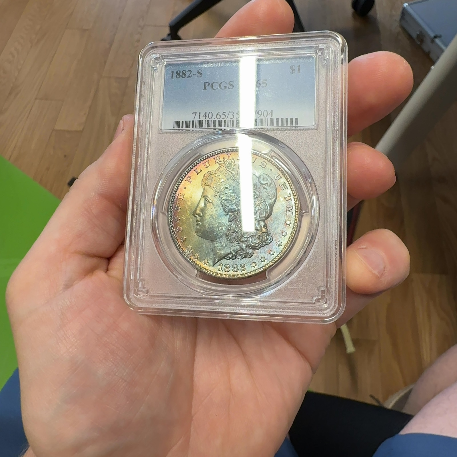 Handheld phone photograph 2 of the 1882-S Morgan Dollar in its holder