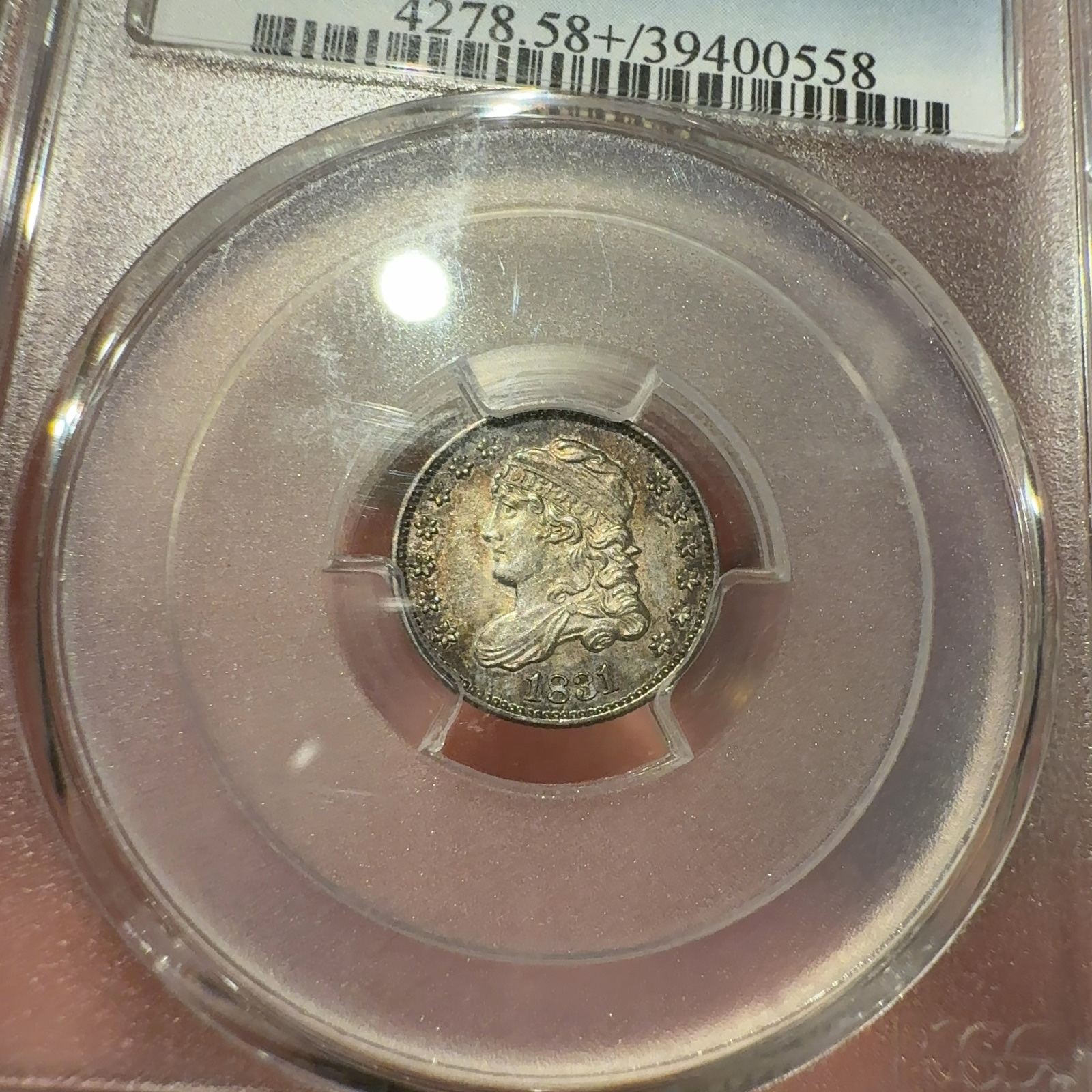 Handheld phone photograph 3 of the 1831 Capped Bust Half Dime in its holder