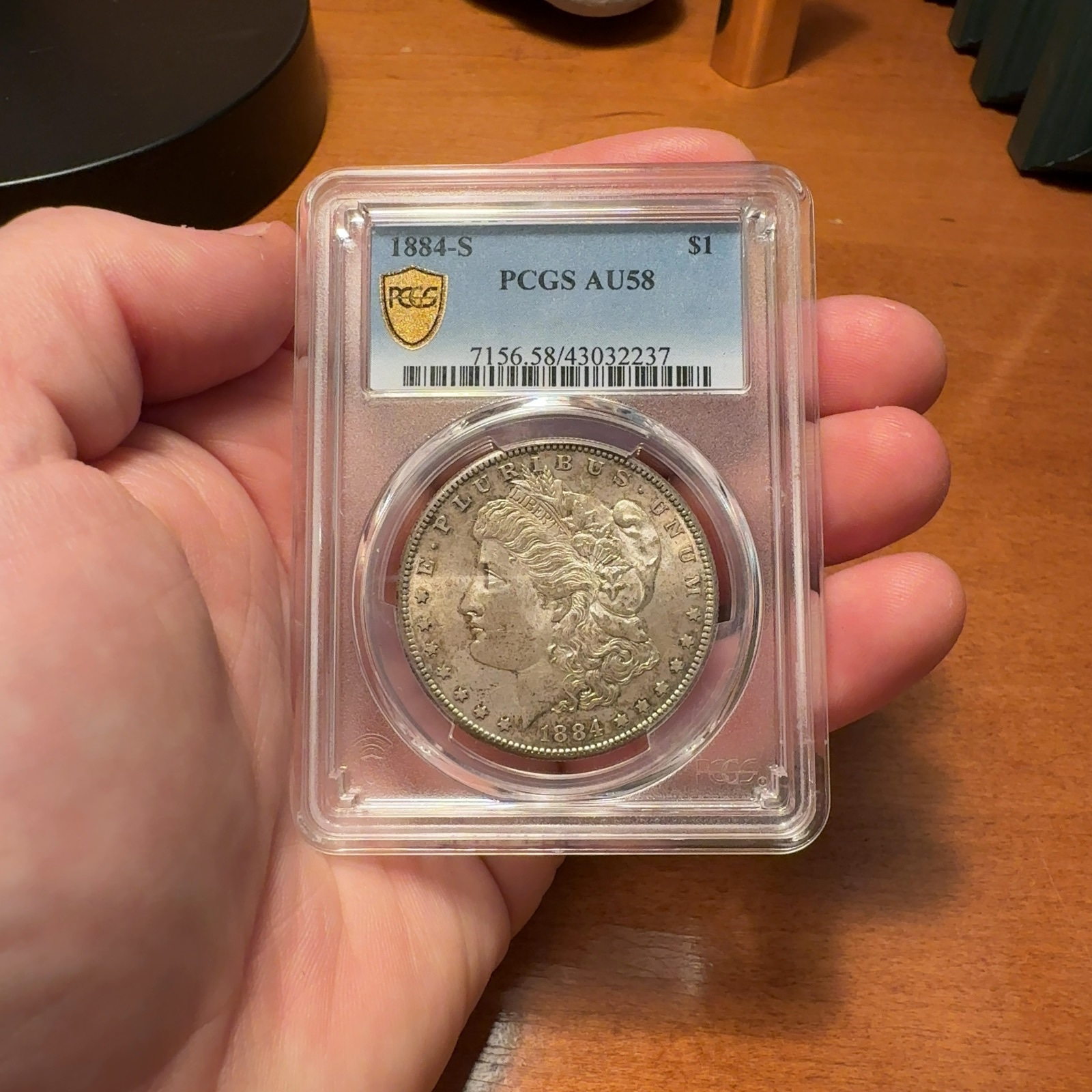 Handheld phone photograph 1 of the 1884-S Morgan Dollar in its holder