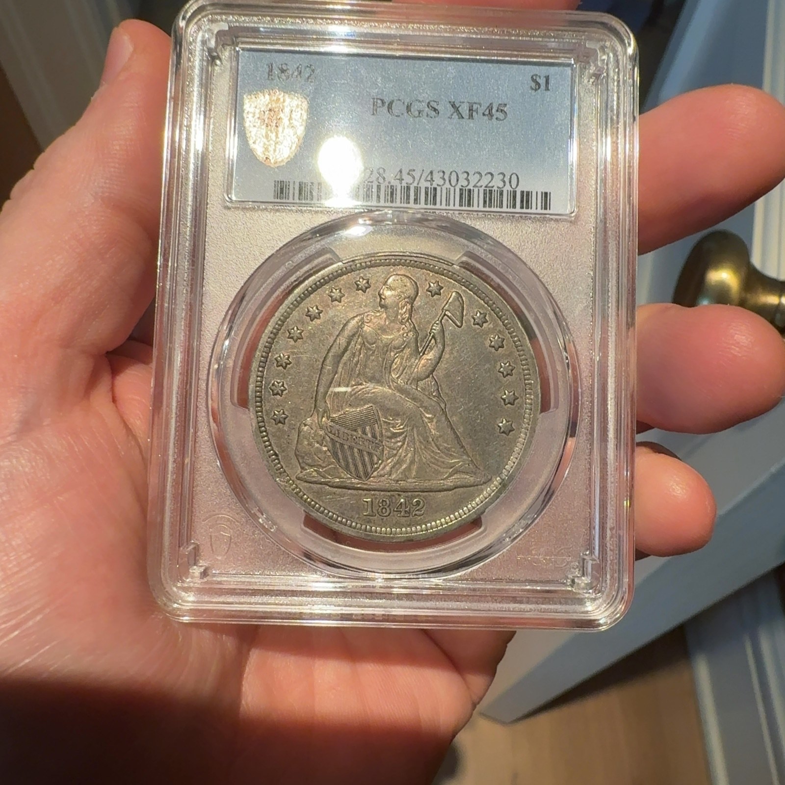 Handheld phone photograph 1 of the 1842 Silver Dollar in its holder