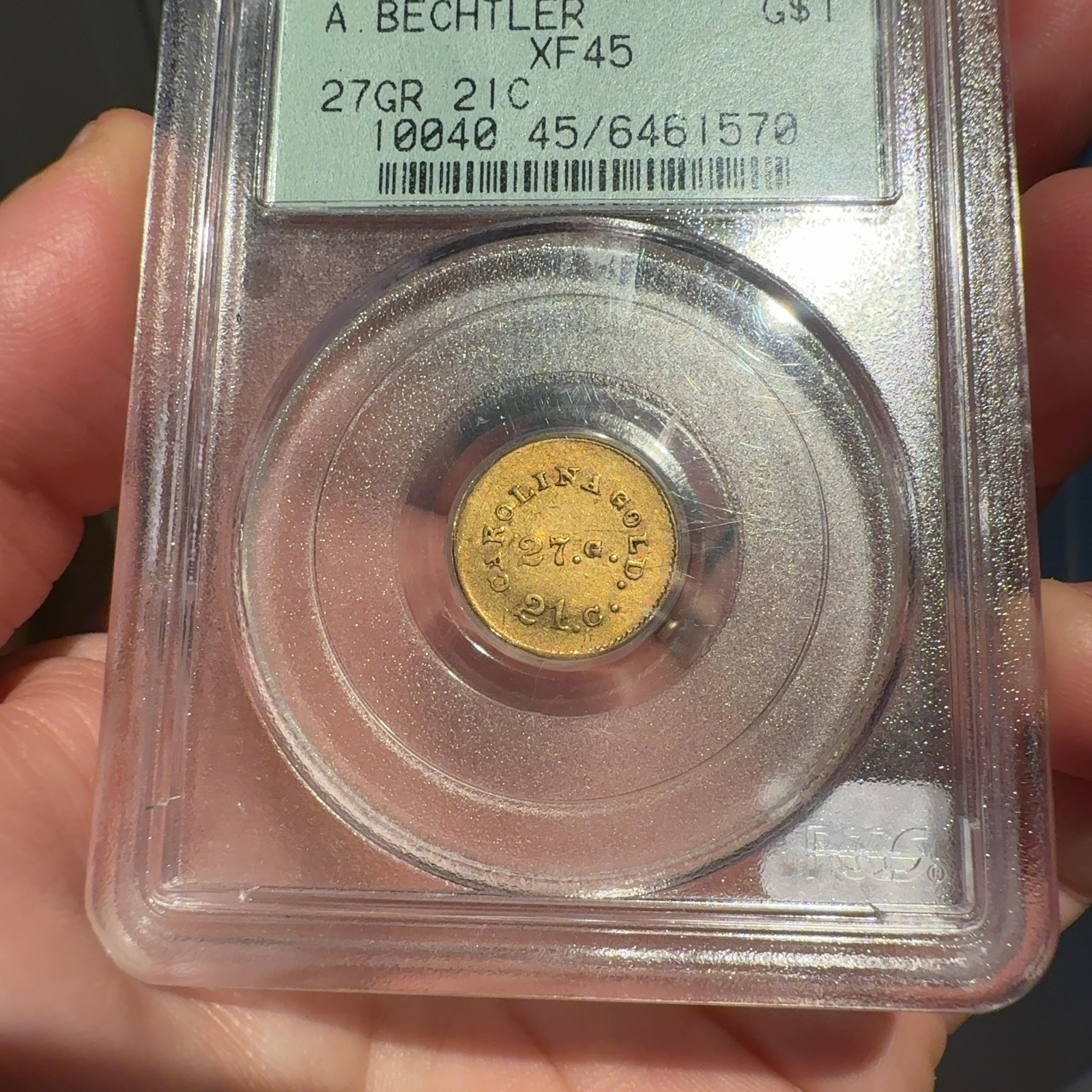 Handheld phone photograph 3 of the 1830s Bechtler Gold Dollar in its holder