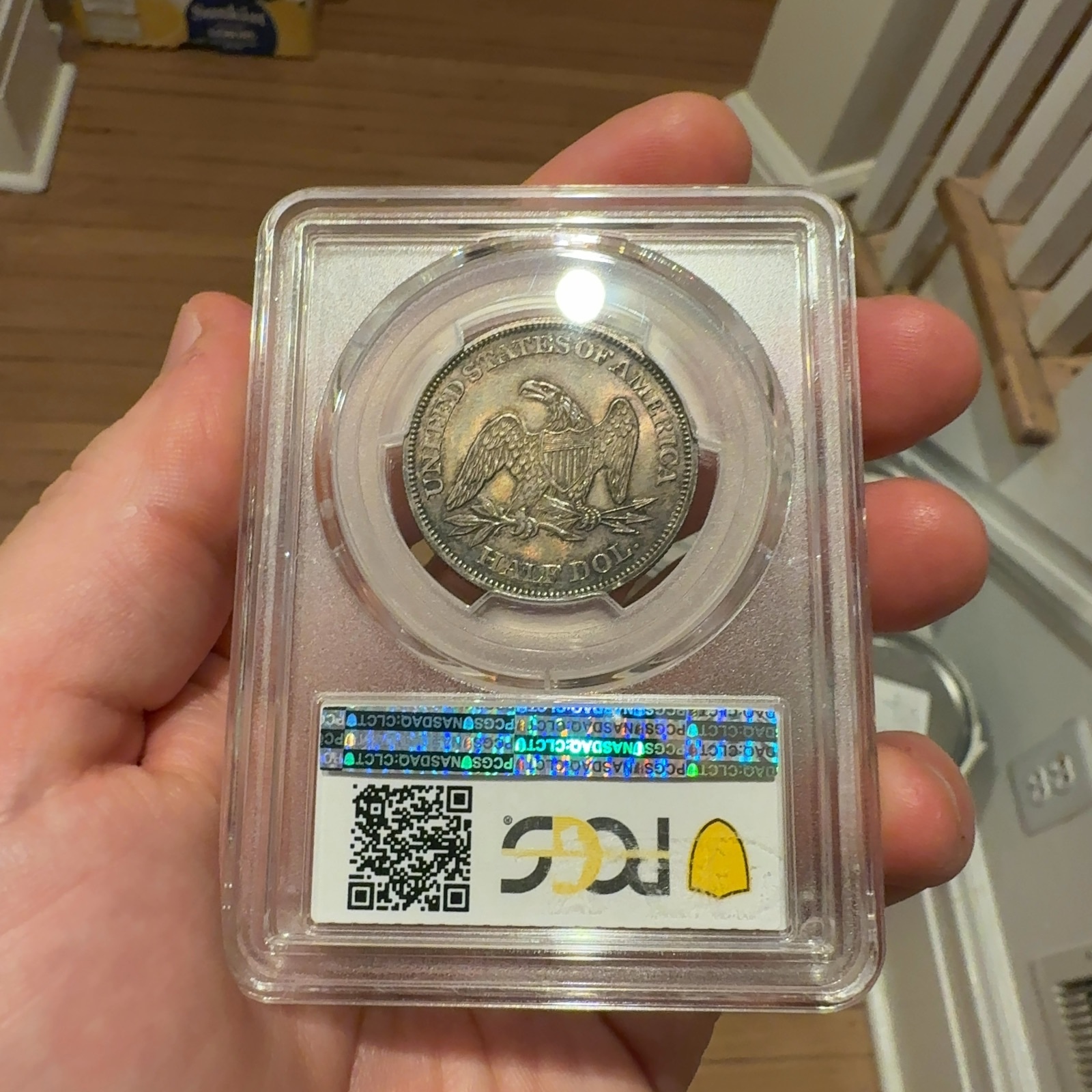 Handheld phone photograph 5 of the 1862 Seated Liberty Half Dollar in its holder