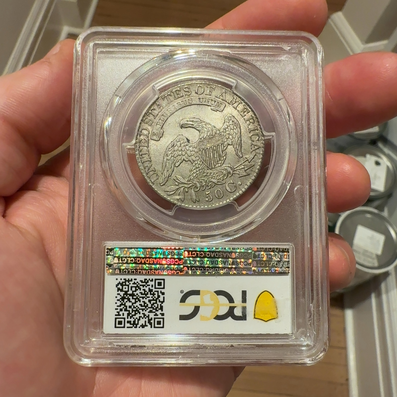 Handheld phone photograph 5 of the 1828 Capped Bust Half Dollar in its holder