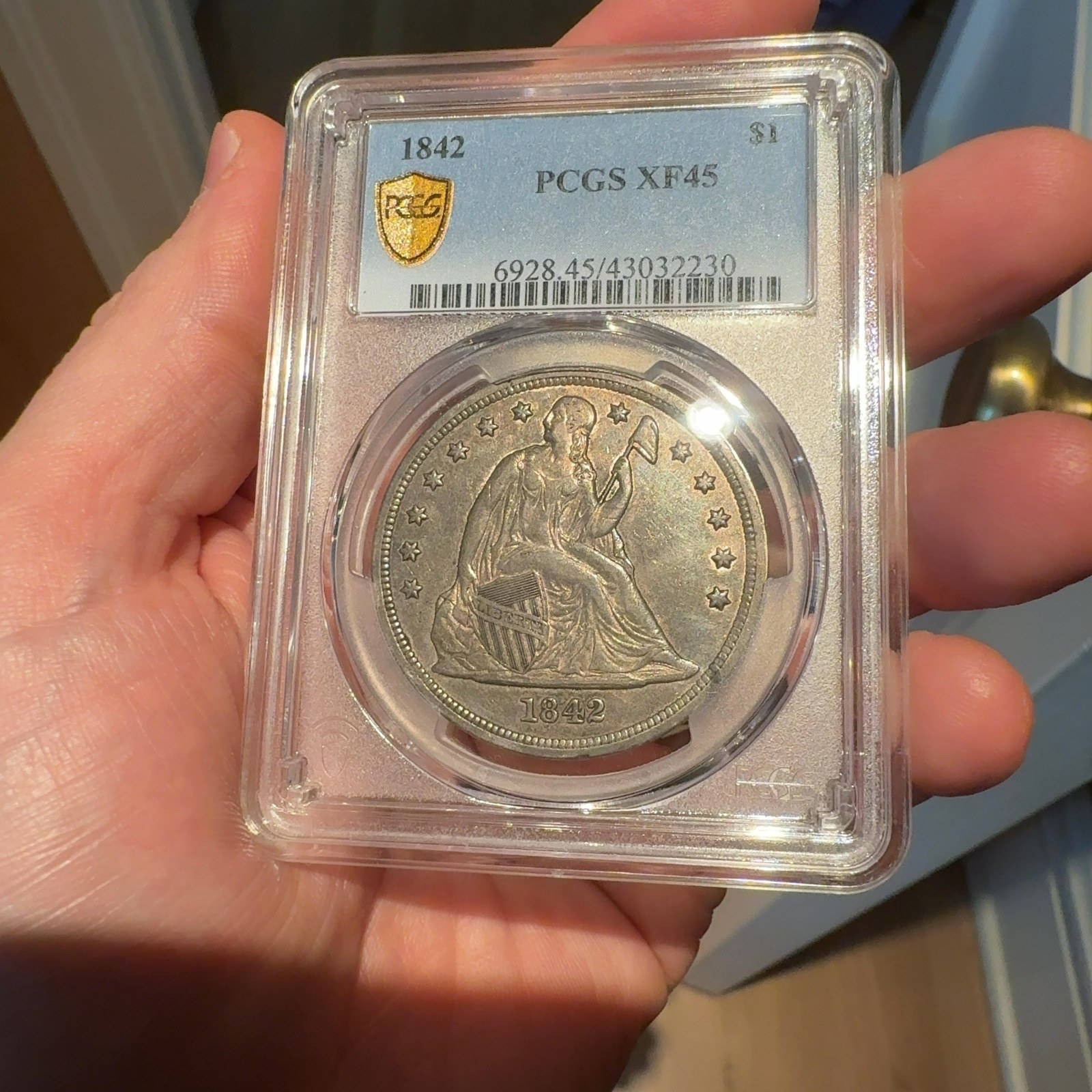 Handheld phone photograph 3 of the 1842 Silver Dollar in its holder