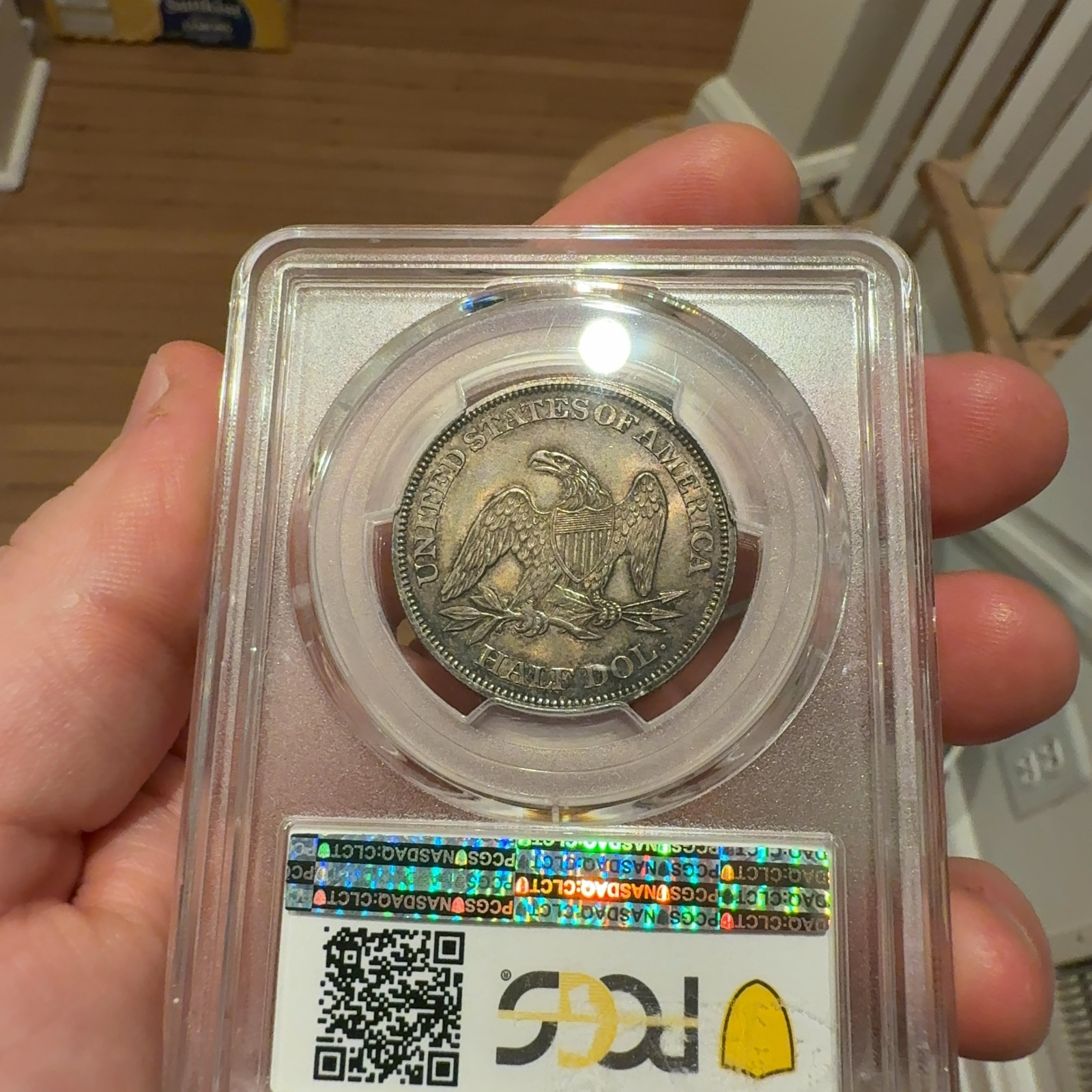Handheld phone photograph 6 of the 1862 Seated Liberty Half Dollar in its holder