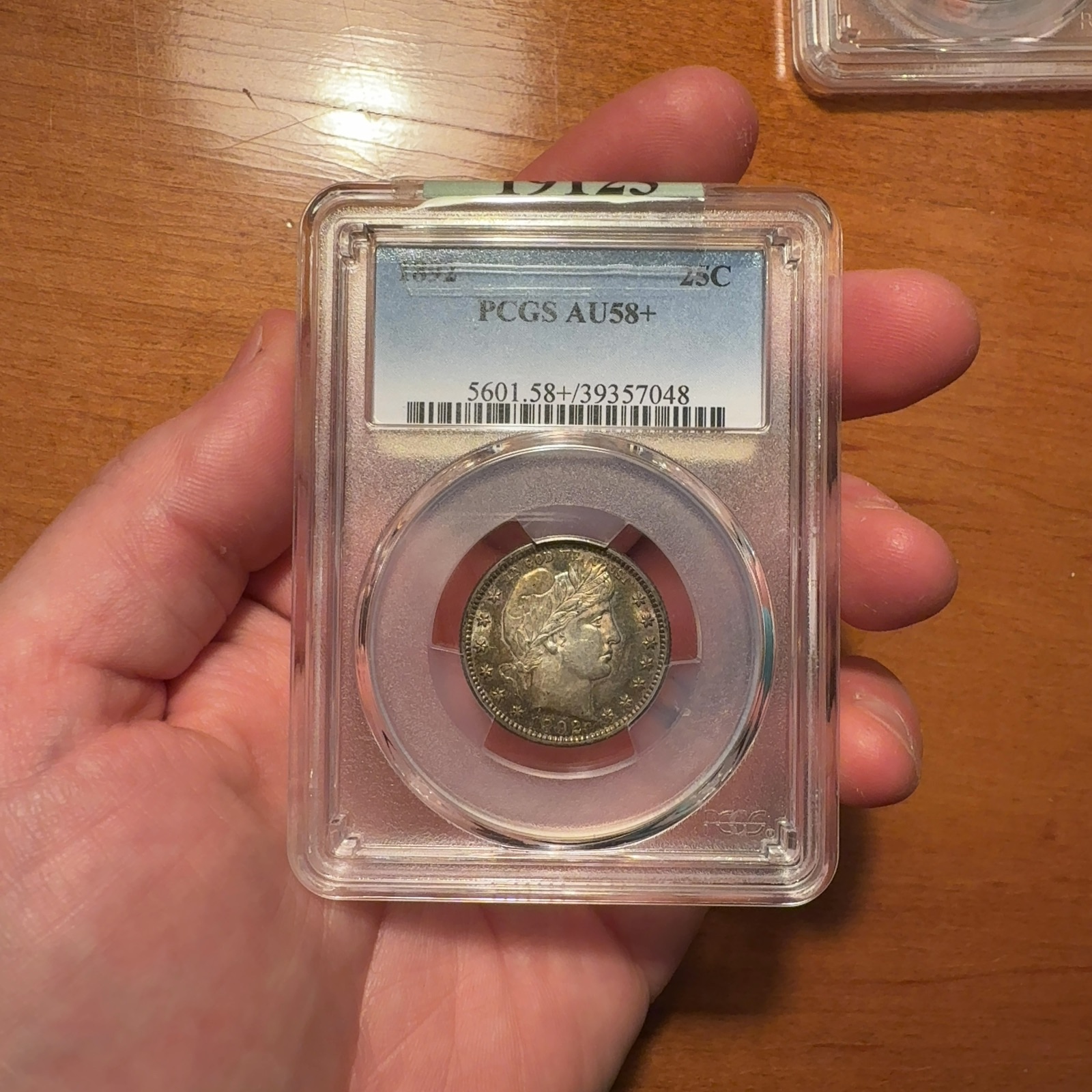 Additional handheld reference photograph 1 of the same 1892 Barber quarter · PCGS AU58+