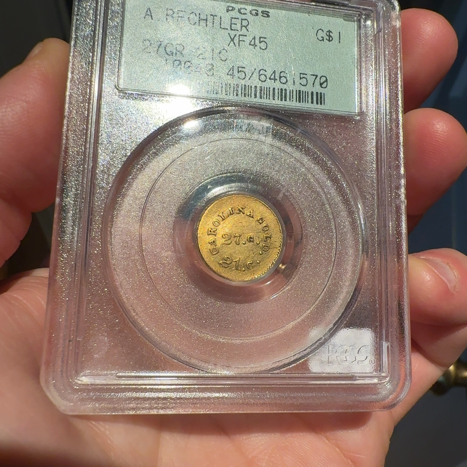 Handheld phone photograph 2 of the 1830s Bechtler Gold Dollar in its holder