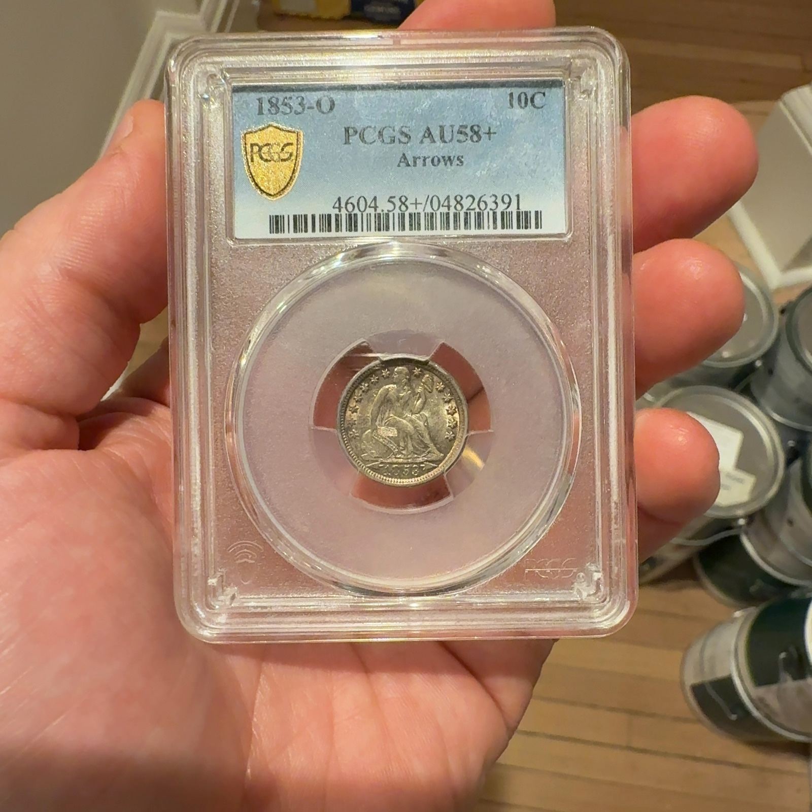 Handheld phone photograph 1 of the 1853-O Seated Liberty Dime in its holder