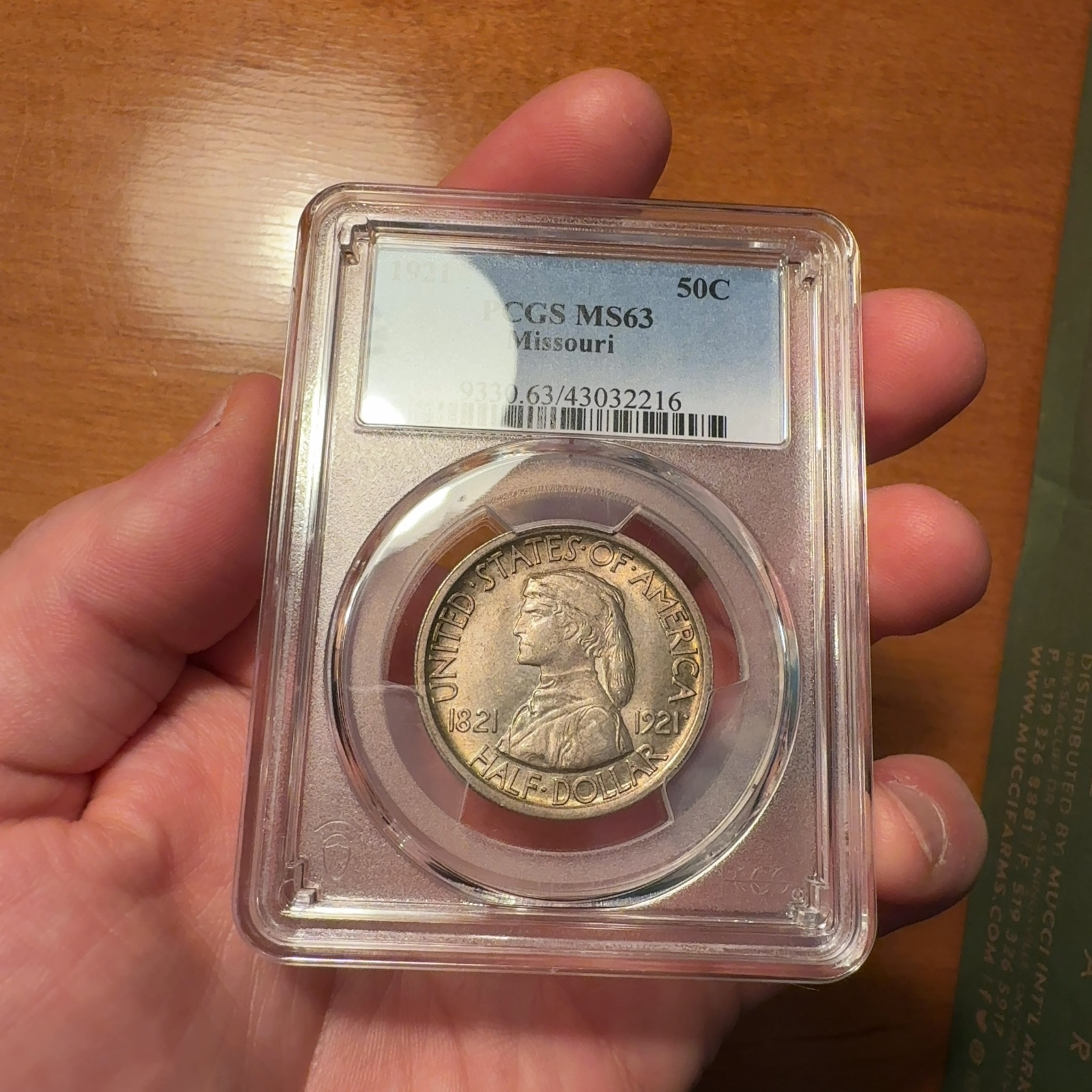 Handheld phone photograph 3 of the 1921 Missouri Half Dollar in its holder