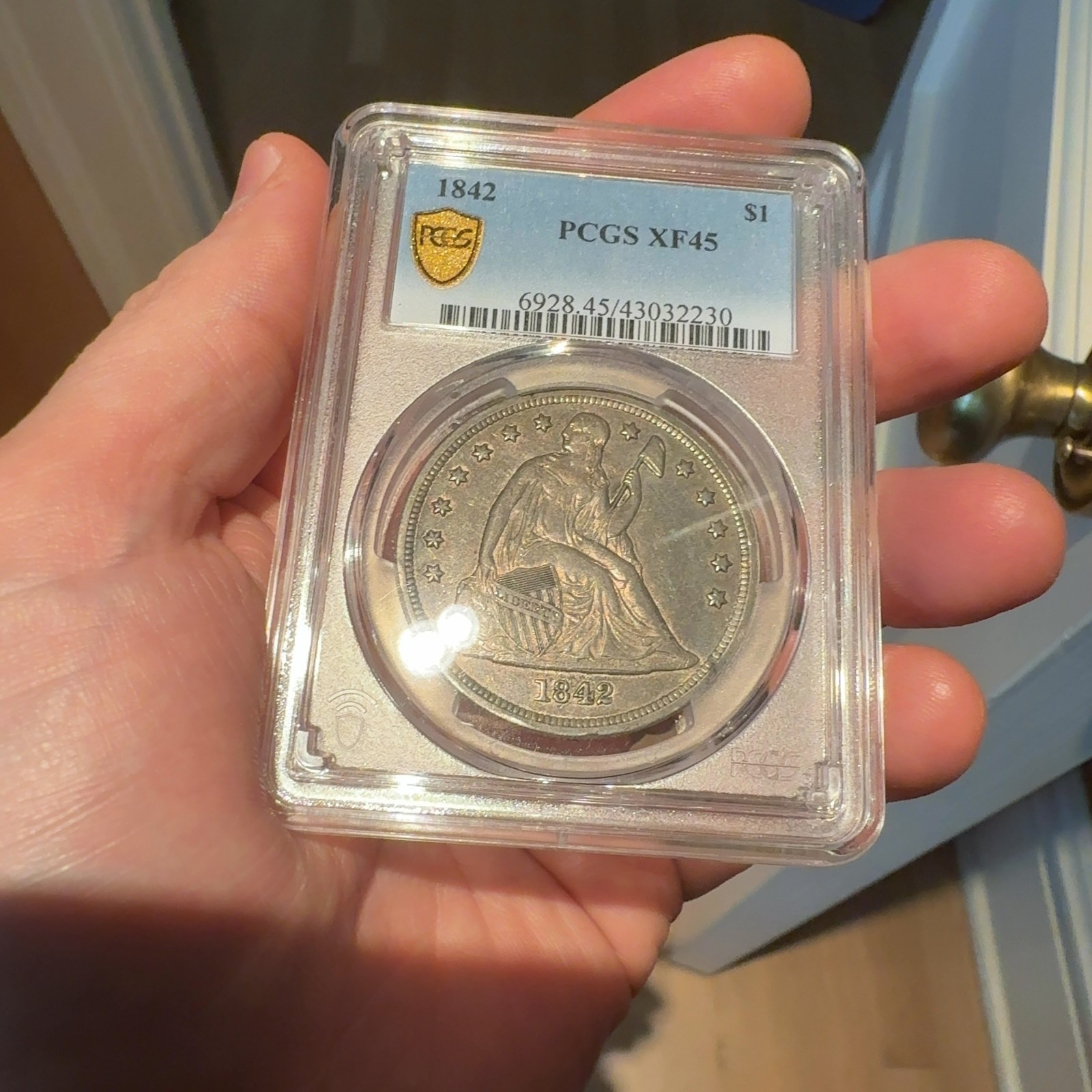 Handheld phone photograph 4 of the 1842 Silver Dollar in its holder