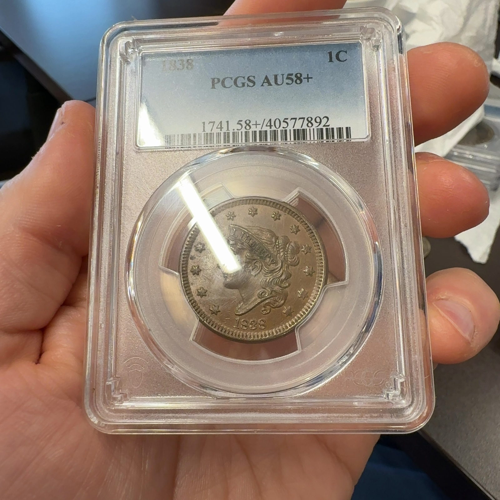 Handheld phone photograph 2 of the 1838 Coronet Large Cent in its holder