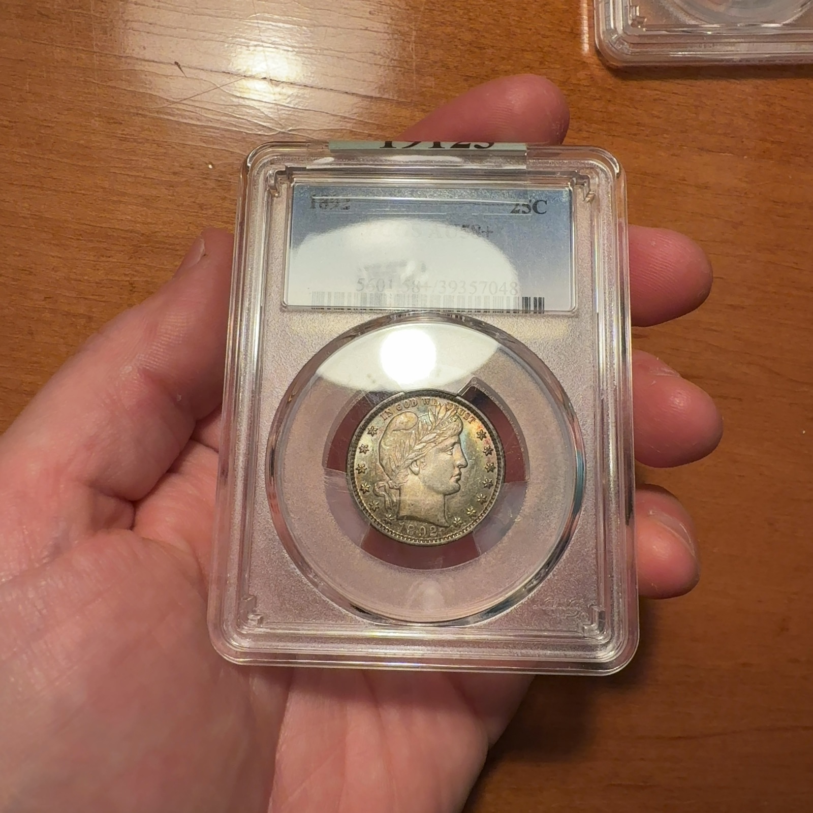 Additional handheld reference photograph 2 of the same 1892 Barber quarter · PCGS AU58+