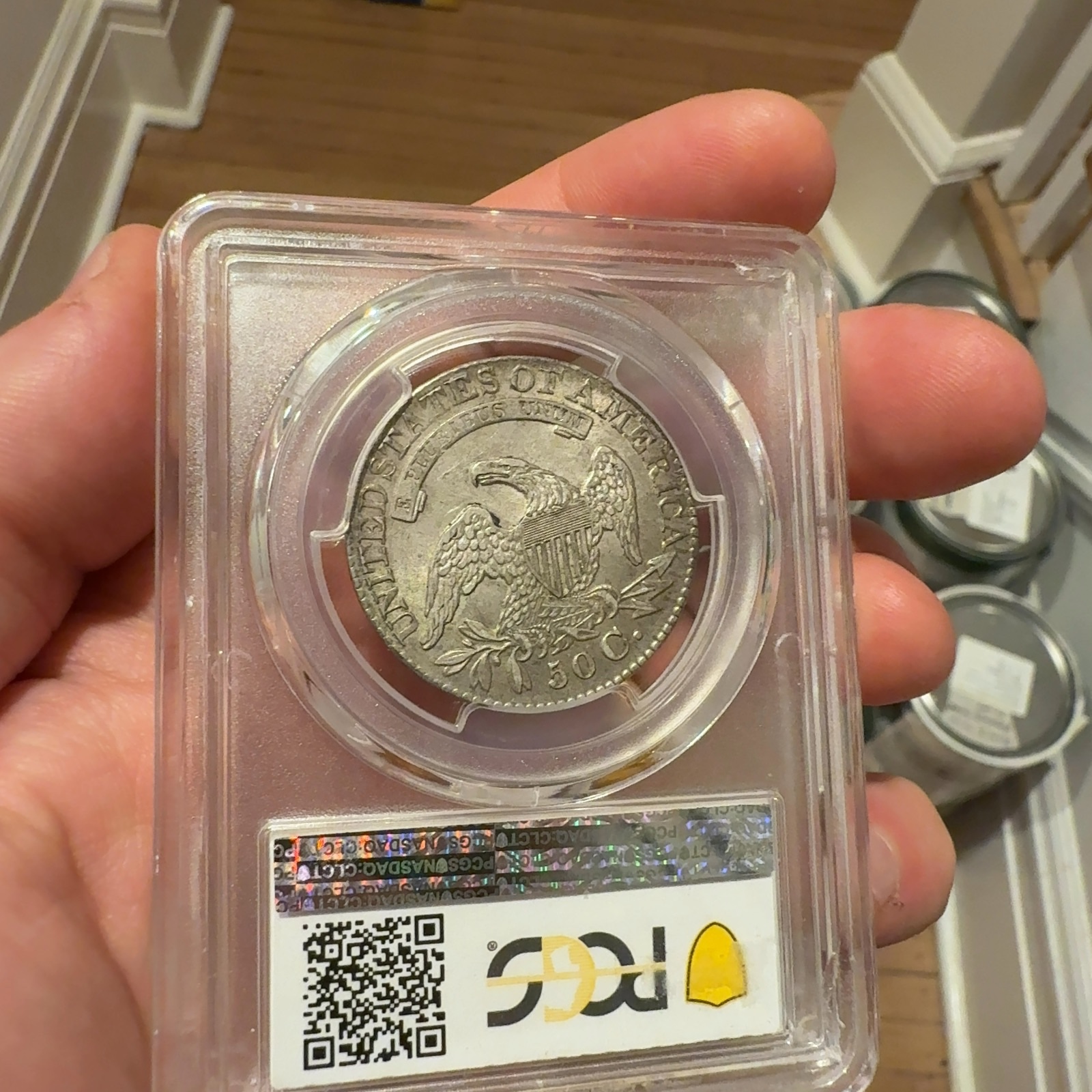 Handheld phone photograph 7 of the 1828 Capped Bust Half Dollar in its holder