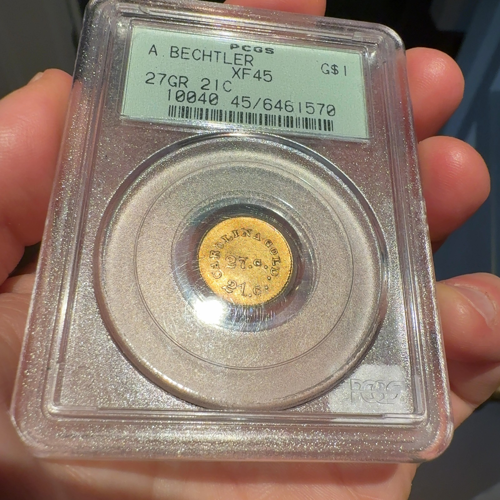 Handheld phone photograph 4 of the 1830s Bechtler Gold Dollar in its holder