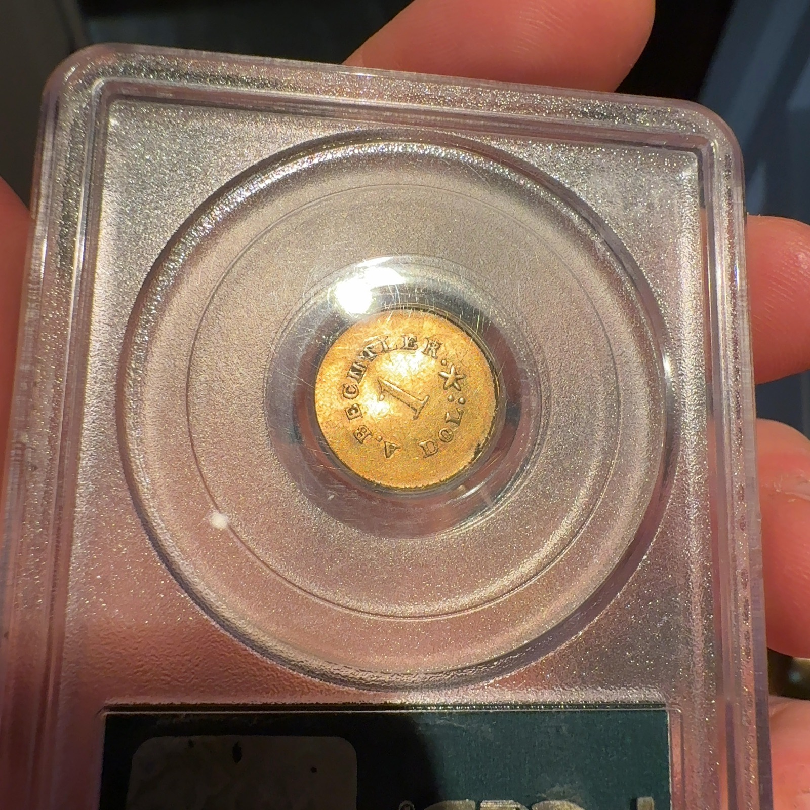 Handheld phone photograph 6 of the 1830s Bechtler Gold Dollar in its holder