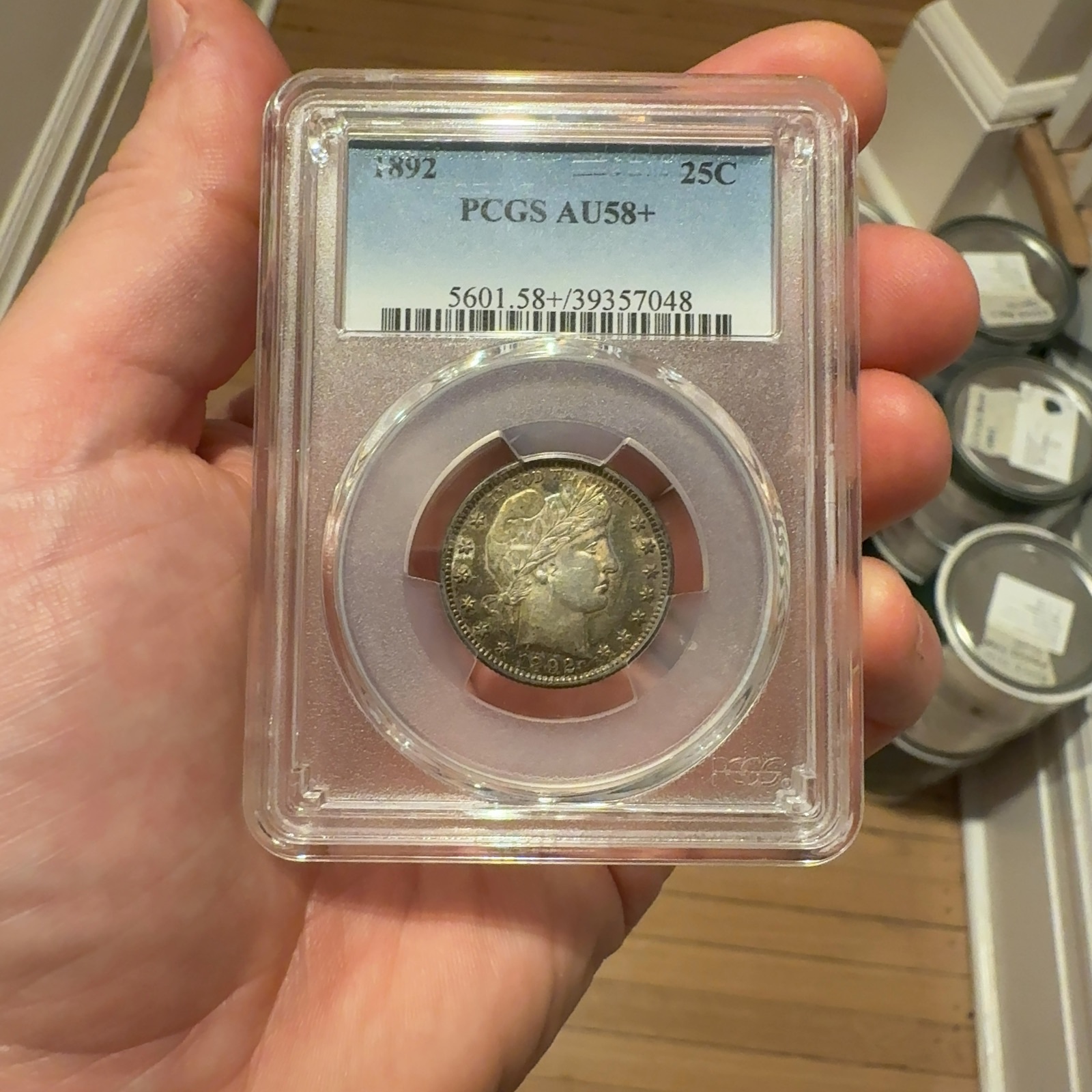 Handheld phone photograph 1 of the 1892 Barber Quarter in its holder