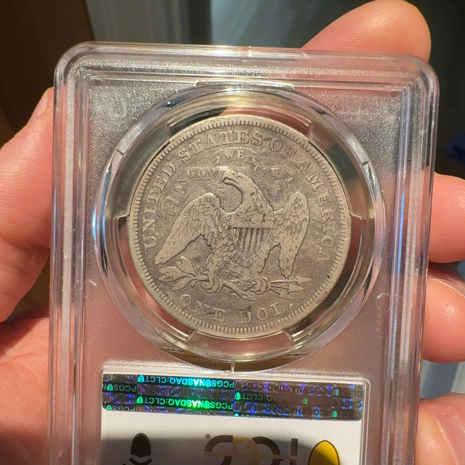 Handheld phone photograph 6 of the 1870-CC Seated Liberty Dollar in its holder