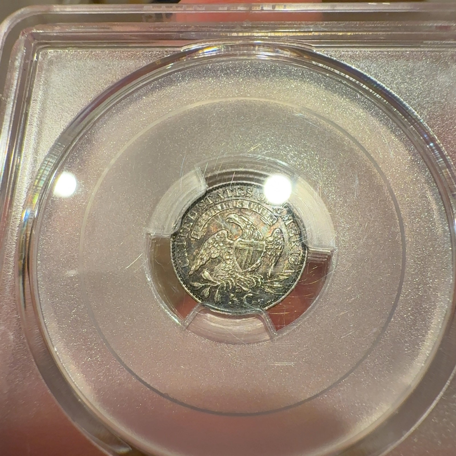 Handheld phone photograph 6 of the 1831 Capped Bust Half Dime in its holder