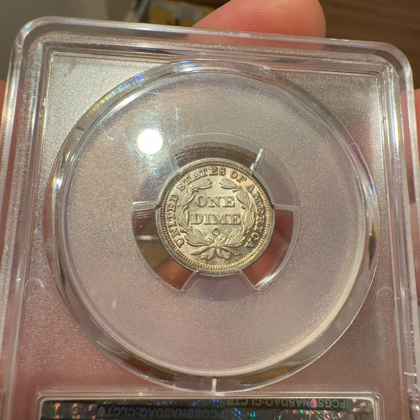 Handheld phone photograph 7 of the 1853-O Seated Liberty Dime in its holder