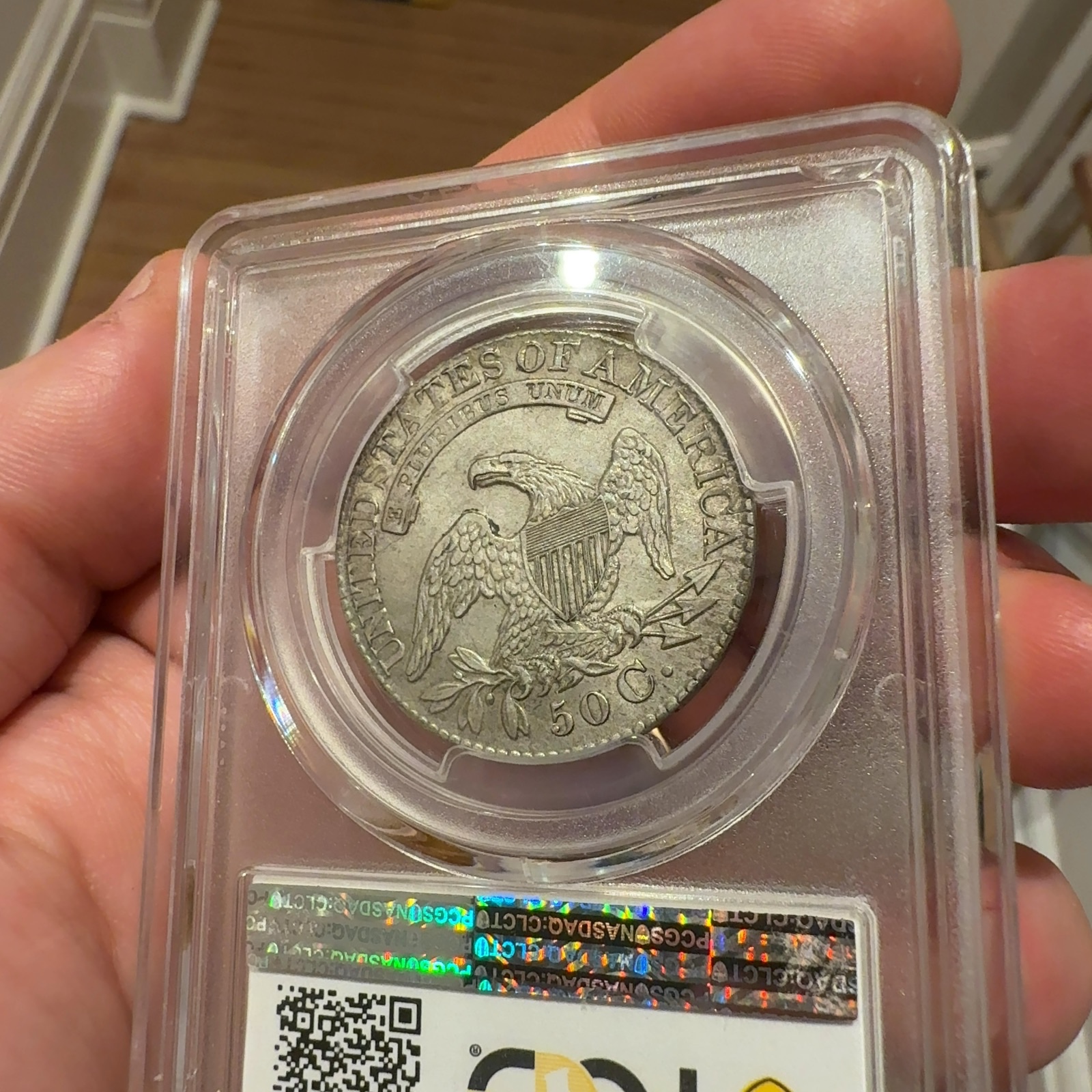 Handheld phone photograph 8 of the 1828 Capped Bust Half Dollar in its holder