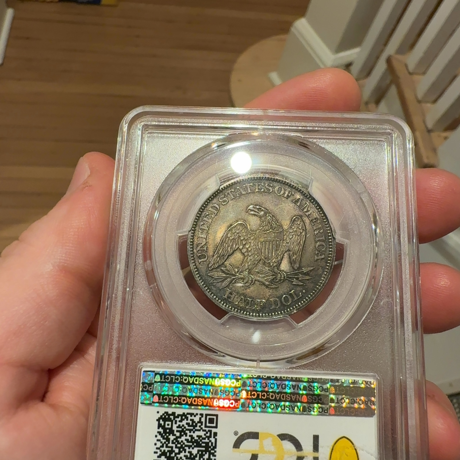 Handheld phone photograph 7 of the 1862 Seated Liberty Half Dollar in its holder