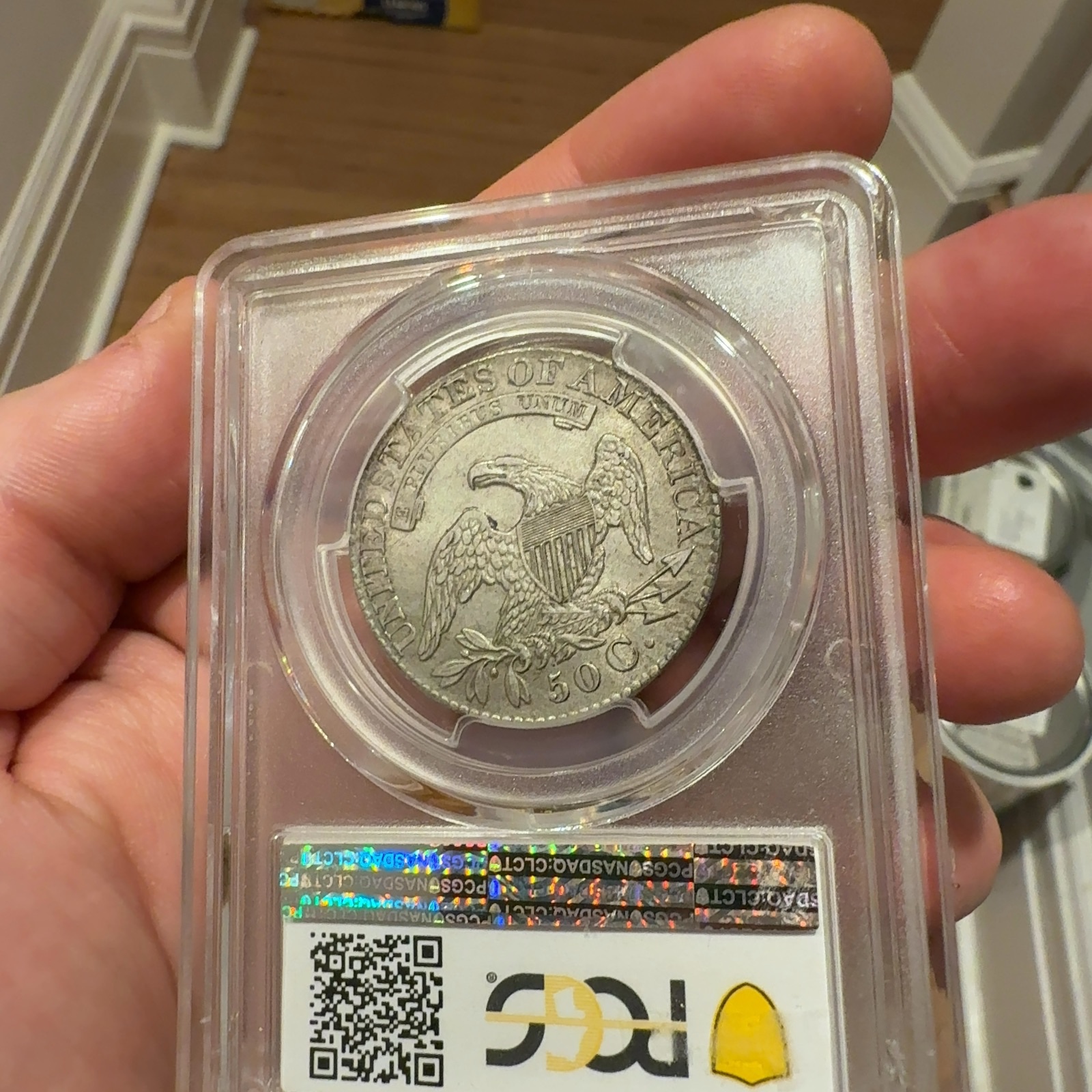 Handheld phone photograph 6 of the 1828 Capped Bust Half Dollar in its holder