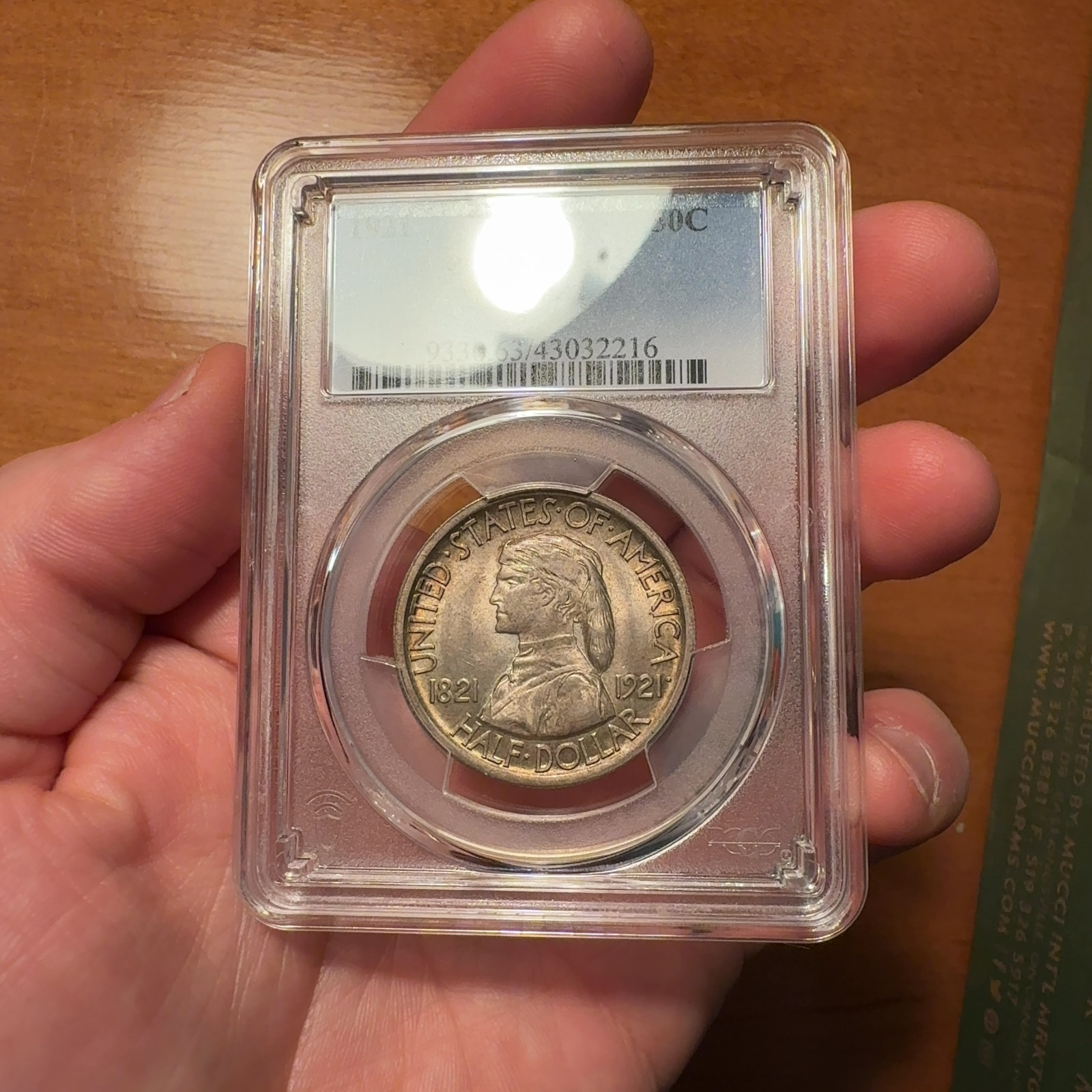 Handheld phone photograph 1 of the 1921 Missouri Half Dollar in its holder