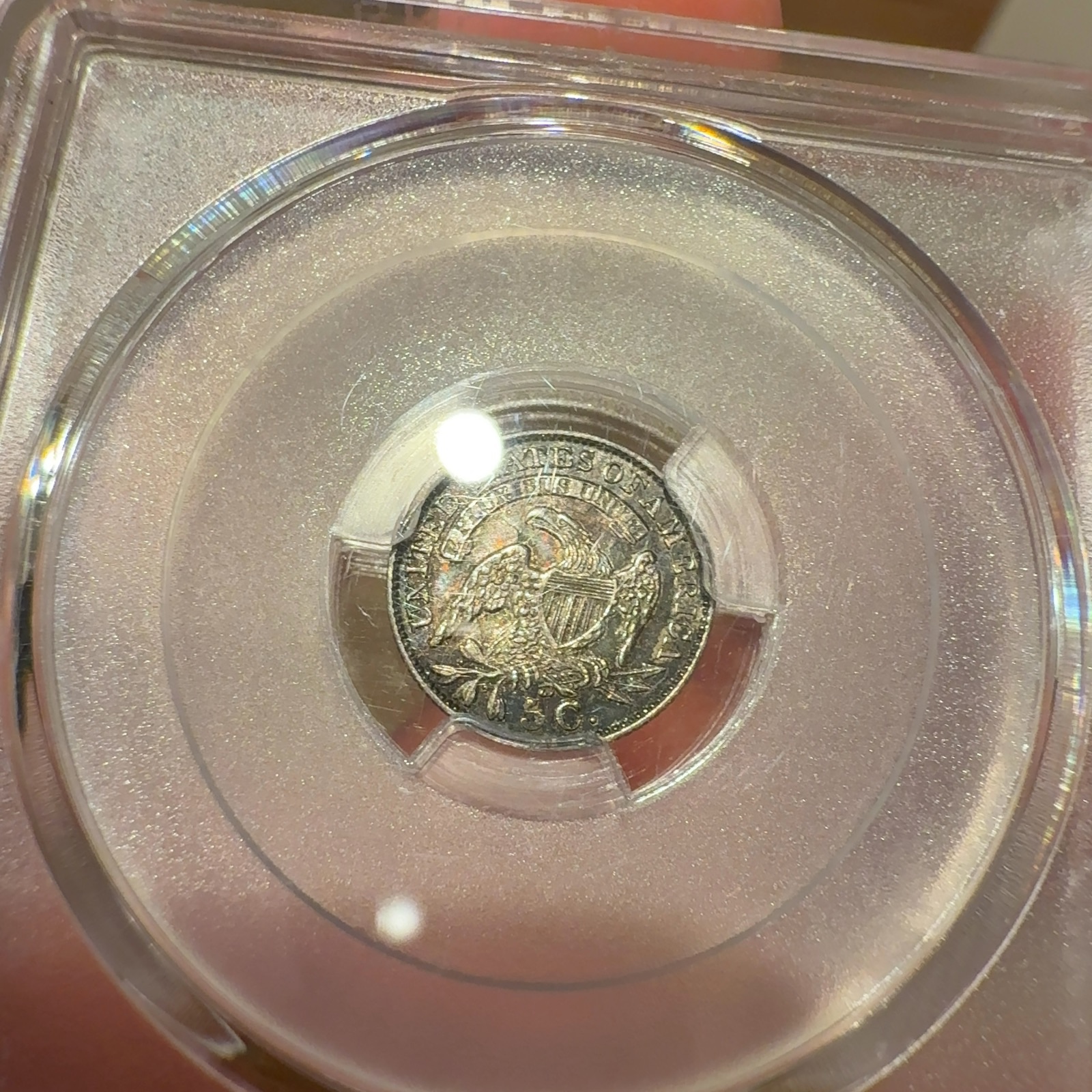 Handheld phone photograph 7 of the 1831 Capped Bust Half Dime in its holder