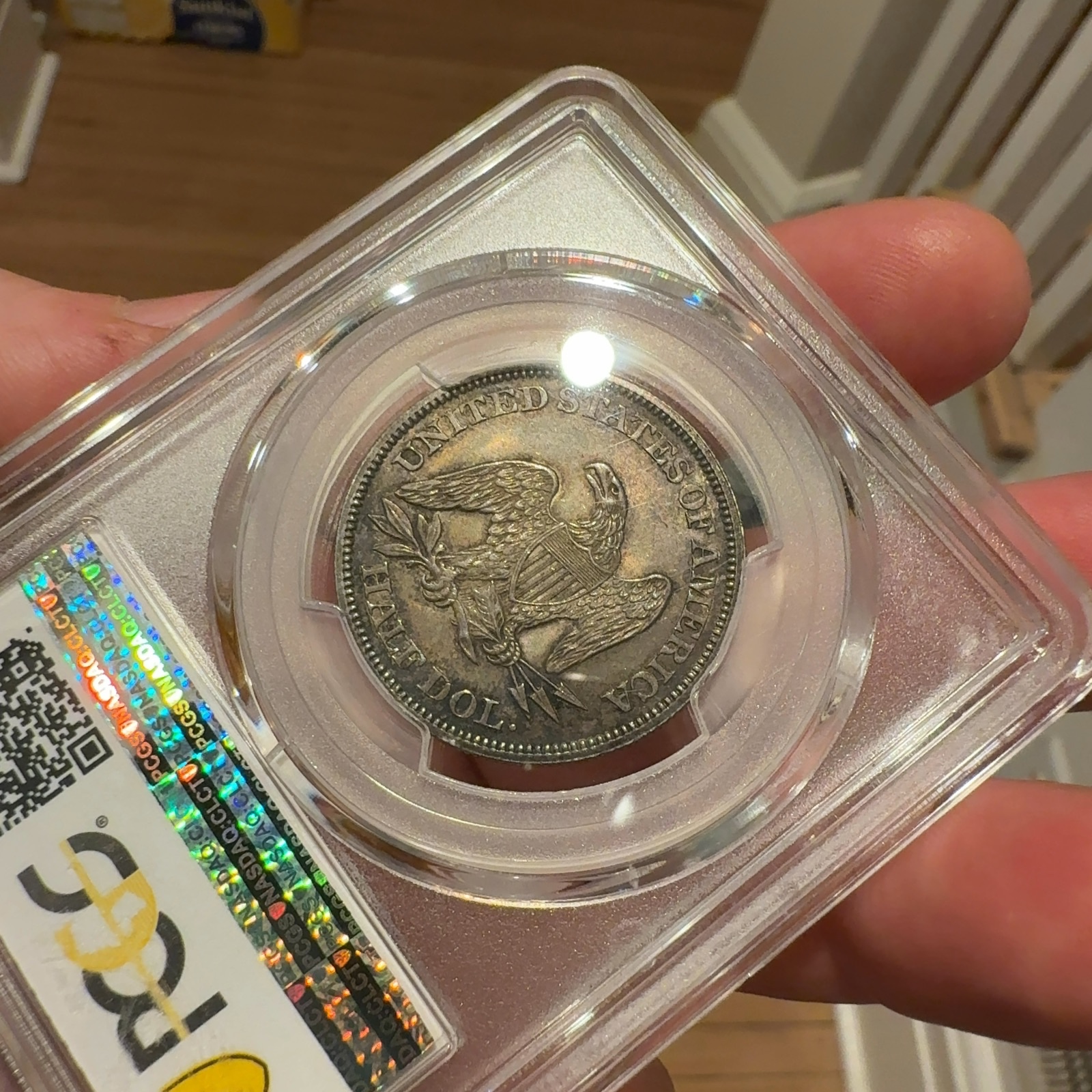 Handheld phone photograph 8 of the 1862 Seated Liberty Half Dollar in its holder