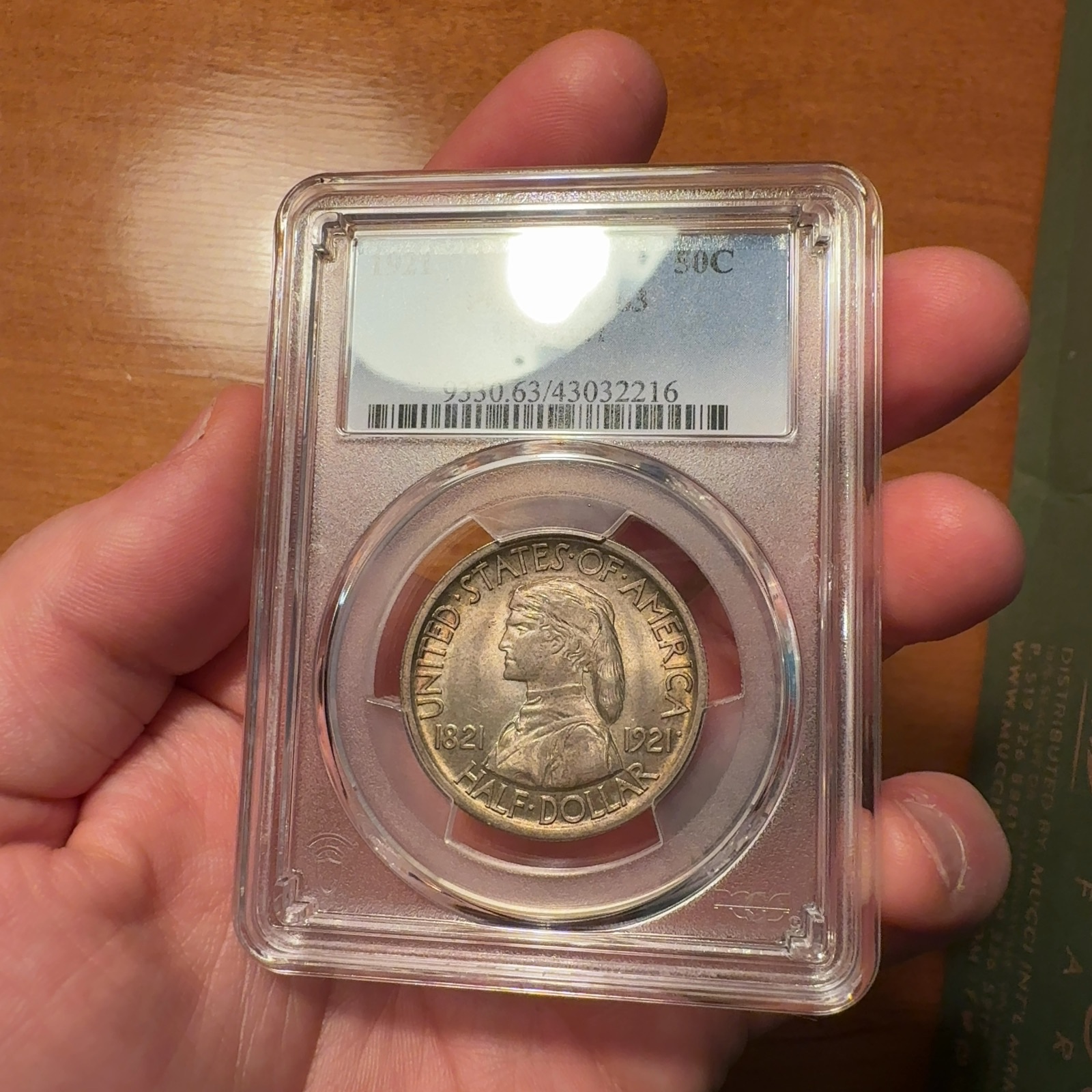 Handheld phone photograph 4 of the 1921 Missouri Half Dollar in its holder