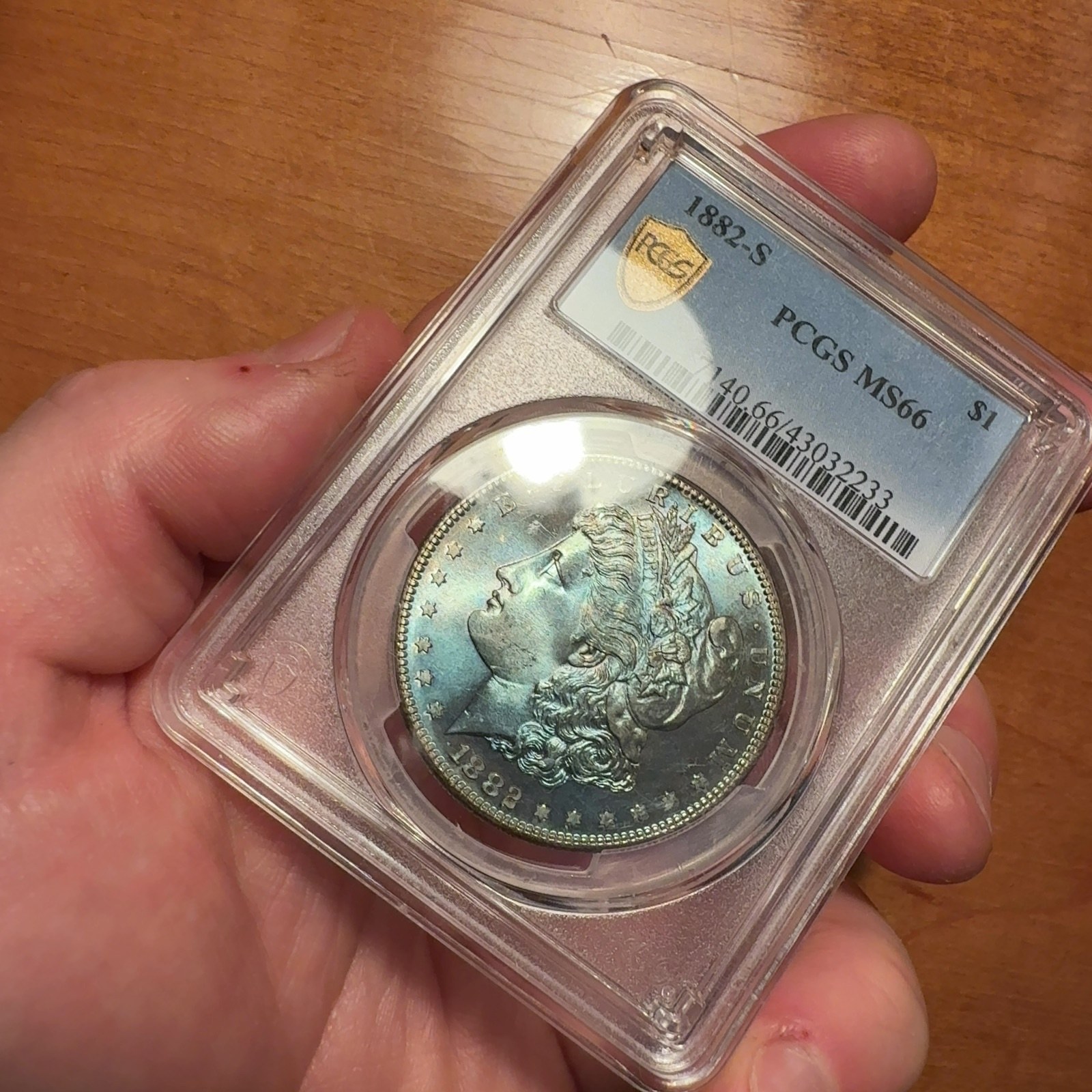 Handheld phone photograph 2 of the 1882-S Silver Dollar in its holder
