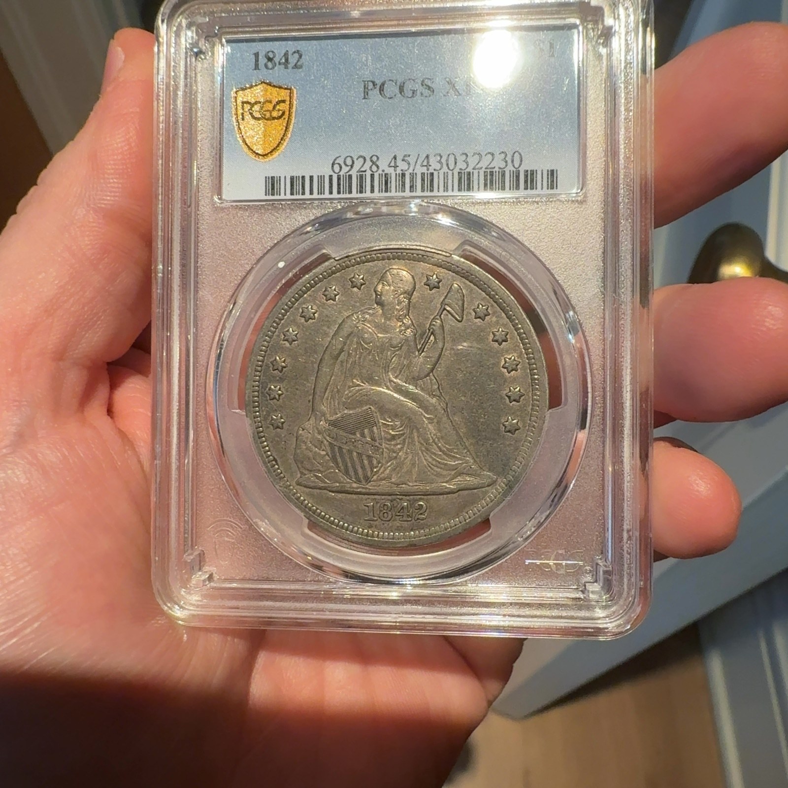 Handheld phone photograph 2 of the 1842 Silver Dollar in its holder