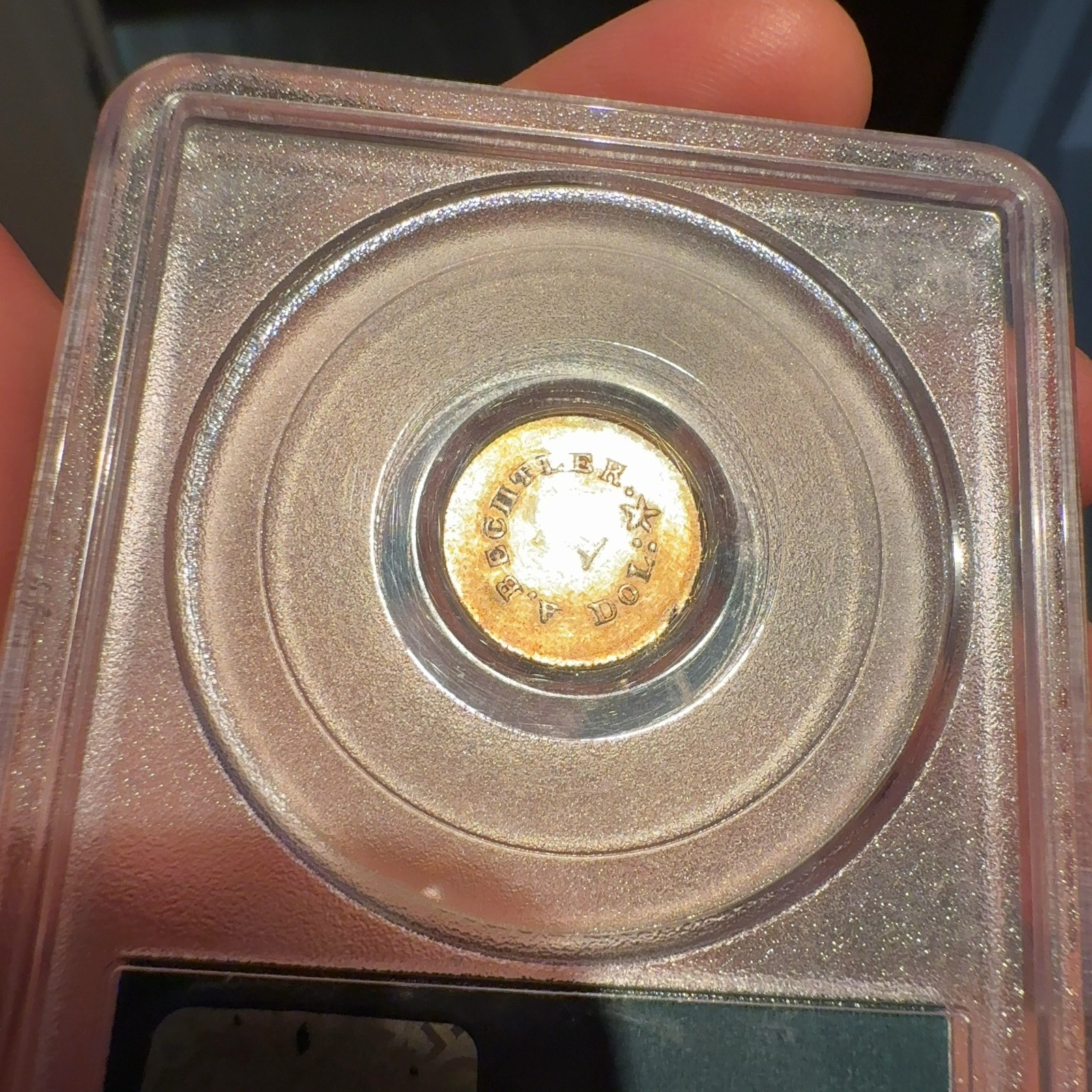 Handheld phone photograph 8 of the 1830s Bechtler Gold Dollar in its holder